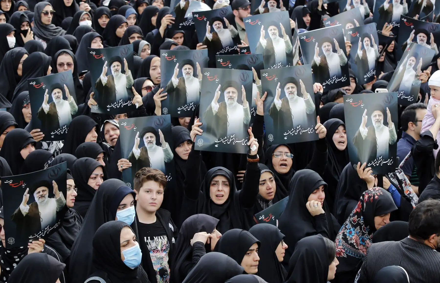 Mujeres iraníes vestidas con chadores negros sostienen carteles del difunto presidente iraní Ebrahim Raisi mientras participan en una ceremonia de luto en Teherán, Irán, este lunes. Foto: EFE