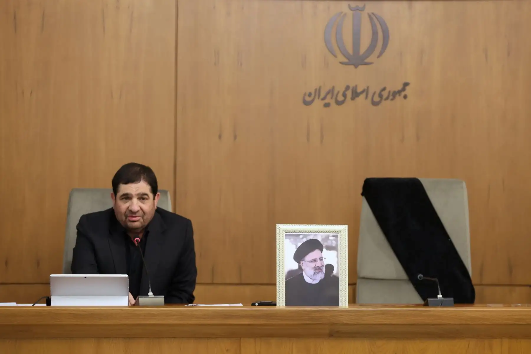 Una fotografía proporcionada por la oficina presidencial iraní, muestra al presidente interino iraní Mohammad Mokhber junto a una fotografía del difunto presidente Ebrahim Raisi encabezando su primera reunión de gabinete en esta función en Tehrán, Irán. Foto: EFE