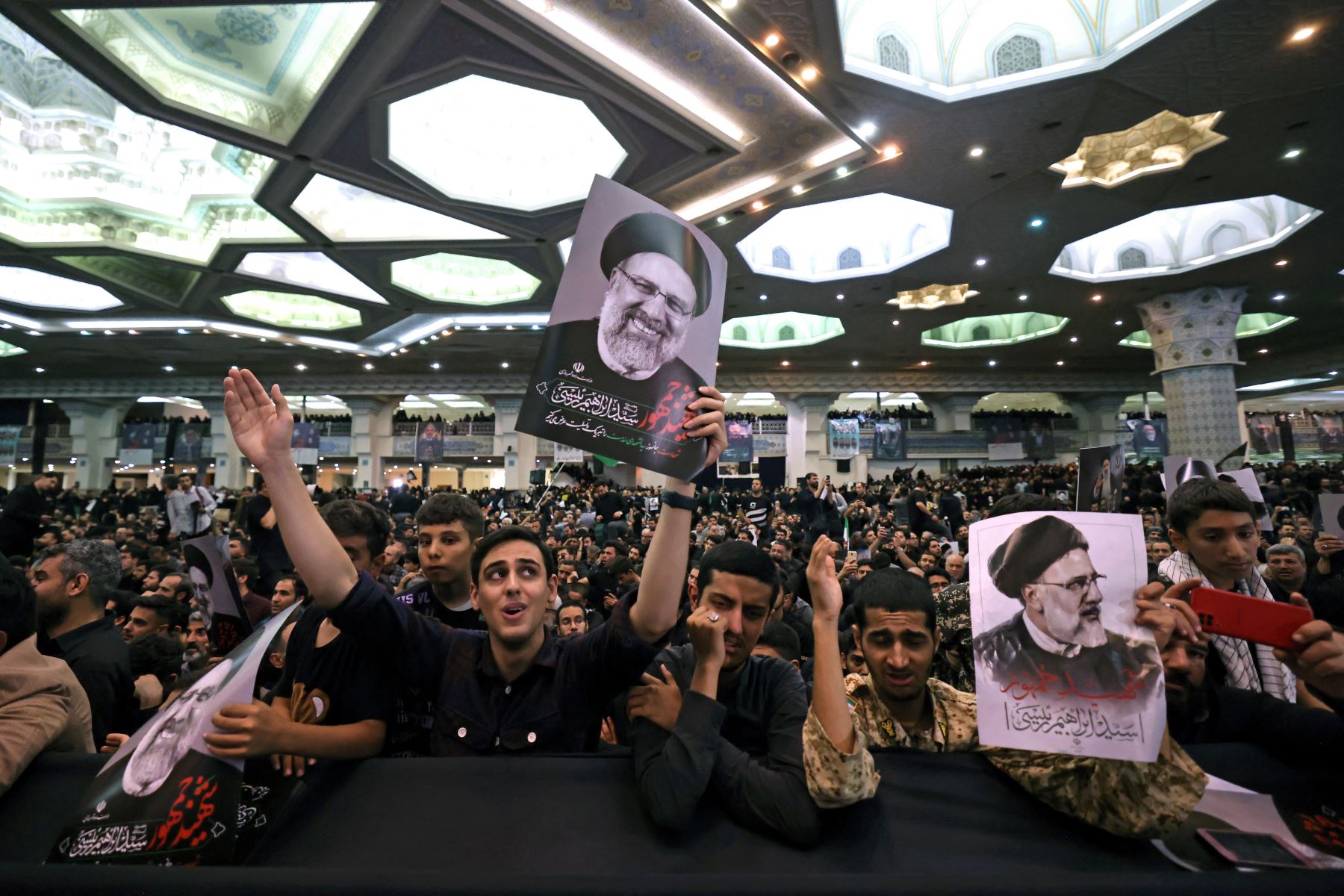 Ciudadanos iraníes sostienen carteles con la imagen de su difunto presidente Ebrahim Raisi durante una ceremonia fúnebre para él y sus compañeros que murieron en un accidente de helicóptero en la mezquita de Mosalia en Teherán. Foto: AFP