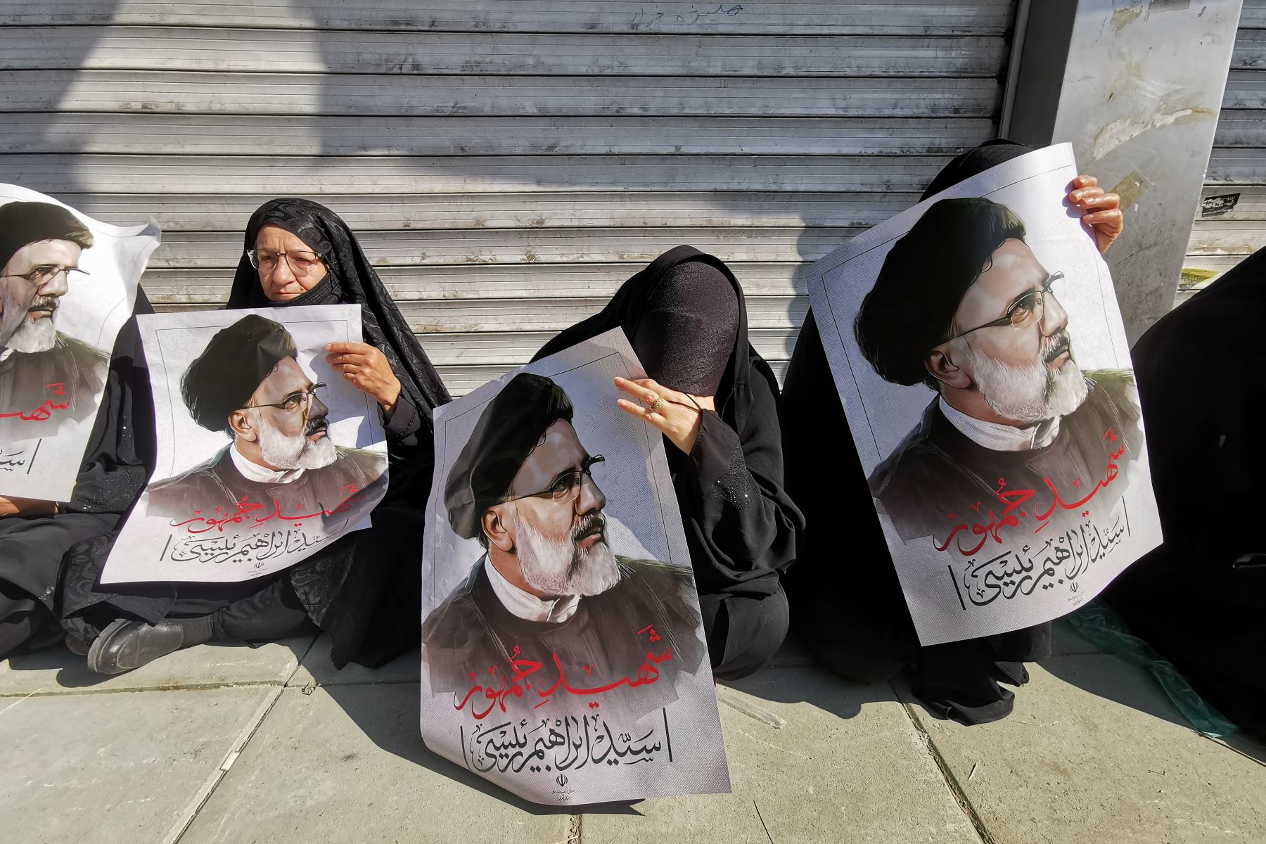 Mujeres iraníes sostienen carteles del presidente Ebrahim Raisi en señal de duelo, durante la ceremonia fúnebre para él y sus compañeros que murieron en un accidente de helicóptero, en Teherán. Foto: AFP