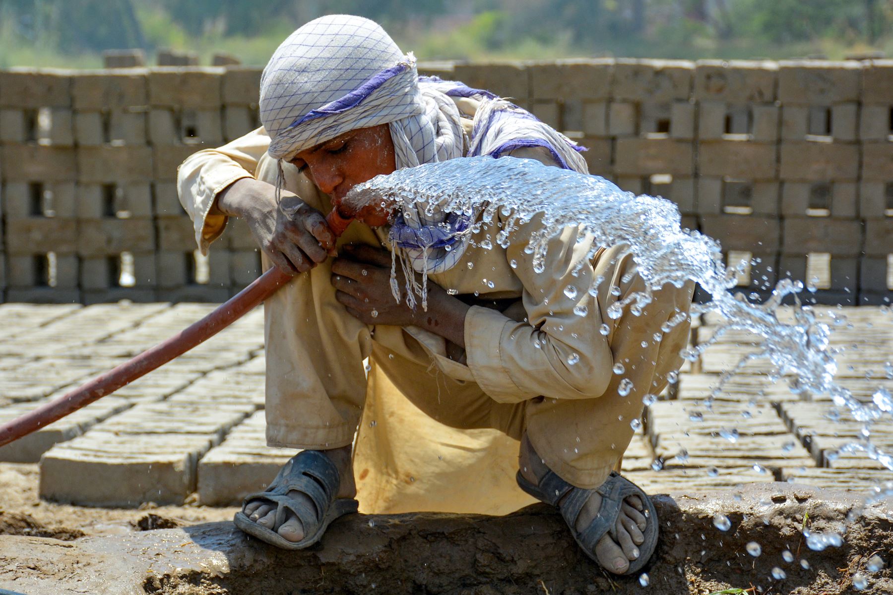 Un trabajador bebe agua de una tubería en un horno de ladrillos durante un caluroso día de verano en Sukkur, provincia de Sindh. El Departamento Meteorológico de Pakistán dijo que se espera que las temperaturas alcancen los 50 grados Celsius en algunas partes. de las zonas rurales de Sindh. Foto: AFP
