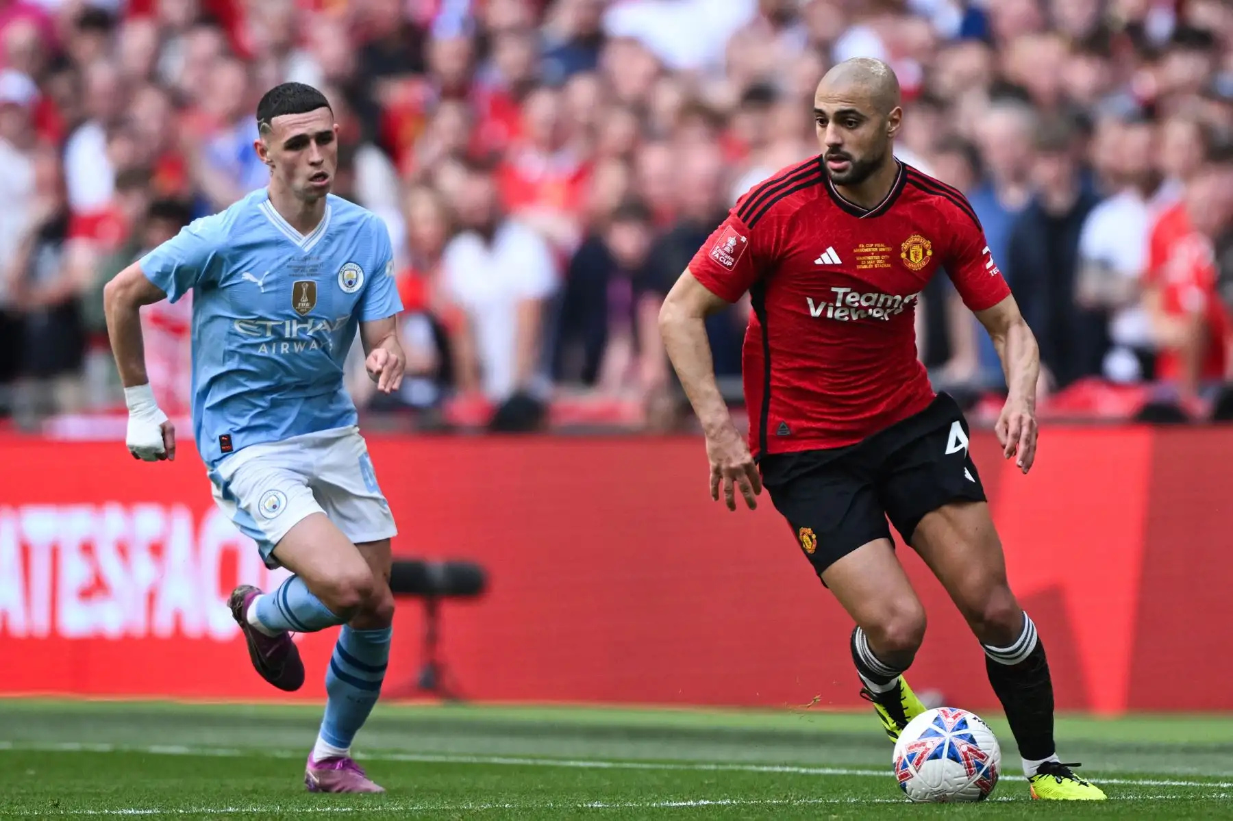 El centrocampista inglés del Manchester City Phil Foden corre detrás del centrocampista marroquí del Manchester United Sofyan Amrabat durante el partido de fútbol final de la Copa FA inglesa entre Manchester City y Manchester United. Foto: ANDINA/AFP