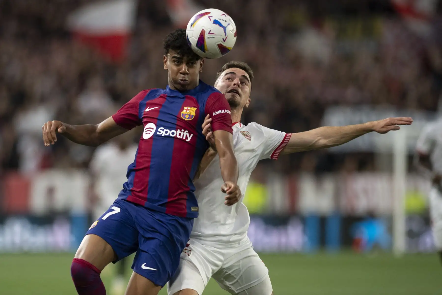 El delantero del Barcelona #27 Lamine Yamal  y el defensor  del Sevilla #3 Adria Giner Pedrosa compiten por un encabezado durante el partido de fútbol de la liga española entre el Sevilla FC y el FC Barcelona en el estadio Ramón Sánchez Pizjuán de Sevilla. Foto: AFP