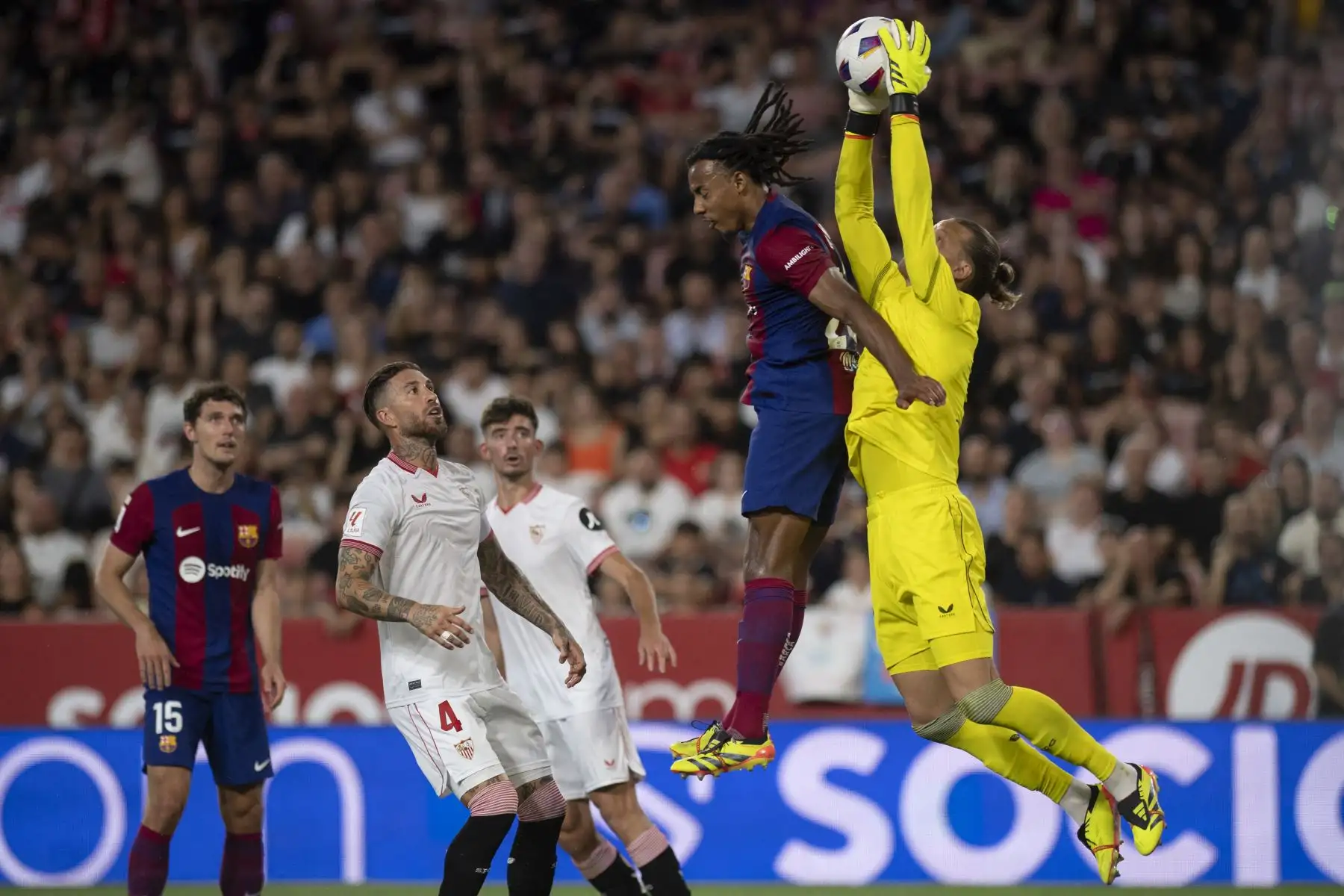 El defensor español del Sevilla #4 Sergio Ramos mira al portero noruego #13 Orjan Nyland salvando el balón junto al defensor francés del Barcelona #23 Jules Kounde (2R) durante el partido de fútbol de la liga española entre el Sevilla FC y el FC Barcelona en el estadio Ramón Sánchez Pizjuán de Sevilla. Foto: AFP