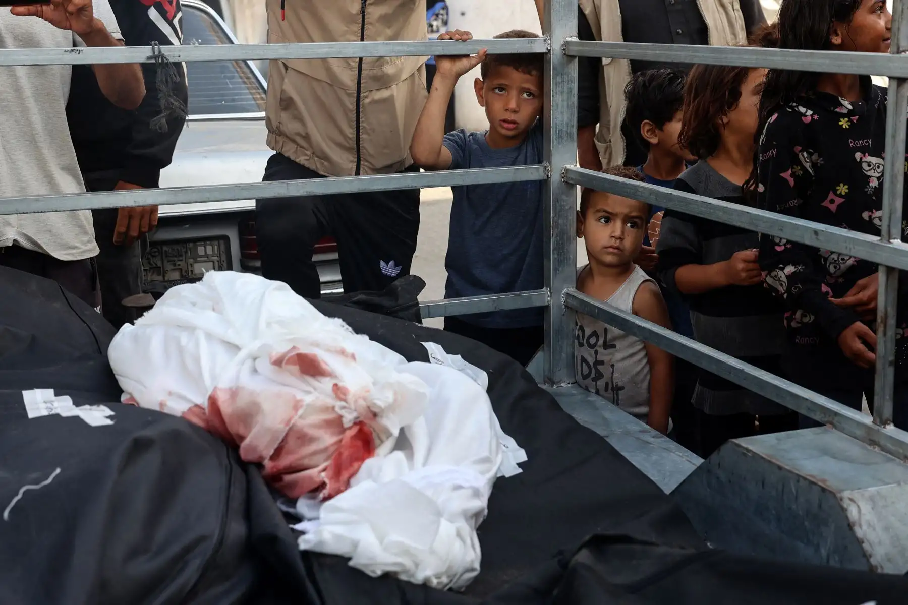 Palestinian children stare at corpses of a child and adults killed in Israeli bombardment, in the area of Tel al-Sultan in Rafah in the southern Gaza Strip on May 26, 2024, amid the ongoing conflict between Israel and the Hamas militant group continues. Foto: AFP