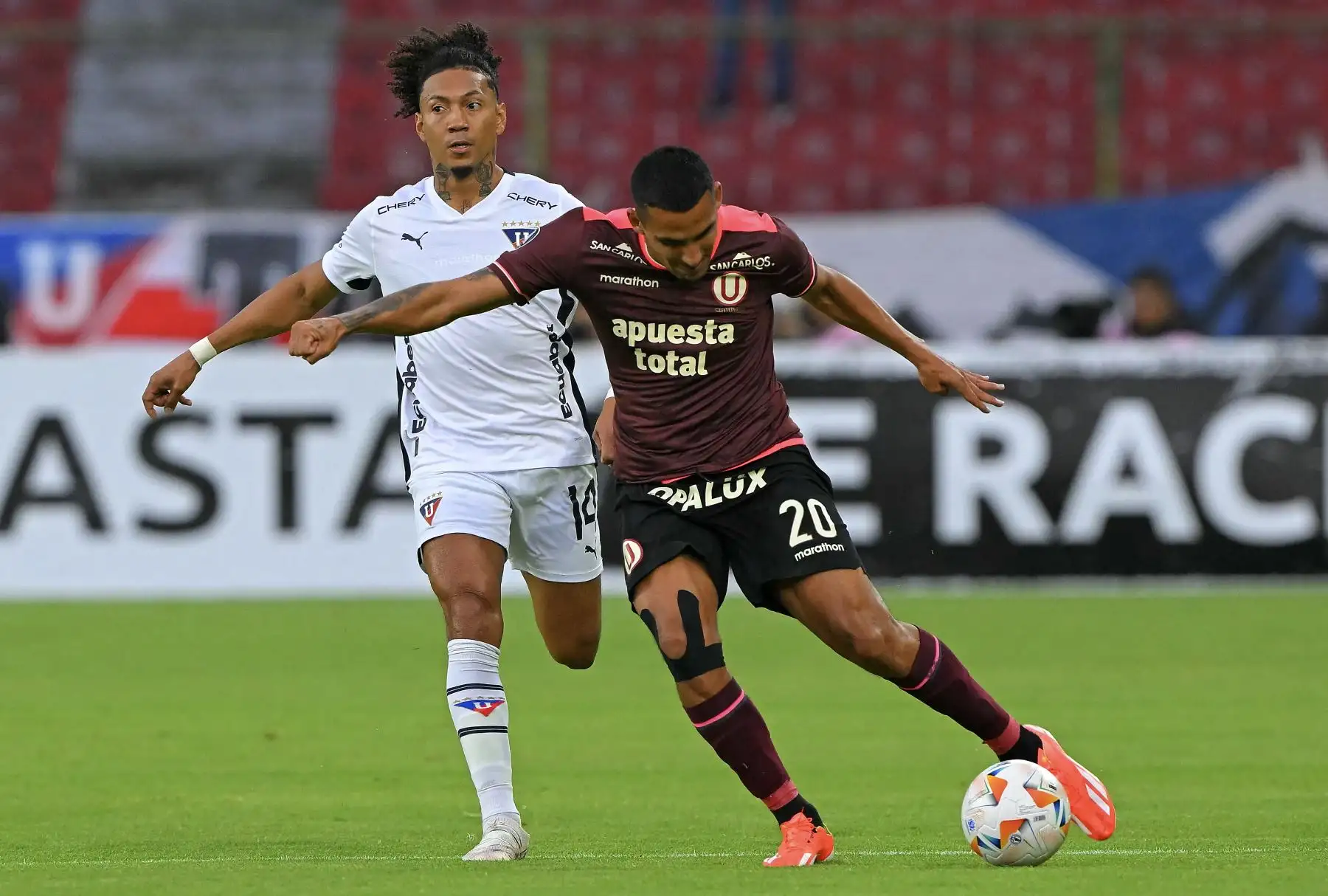 El defensor de la Liga de Quito, José Quintero, y el delantero del Universitario, Alex Valera, luchan por el balón durante el partido de fútbol de vuelta de la fase de grupos de la Copa Libertadores. Foto: AFP