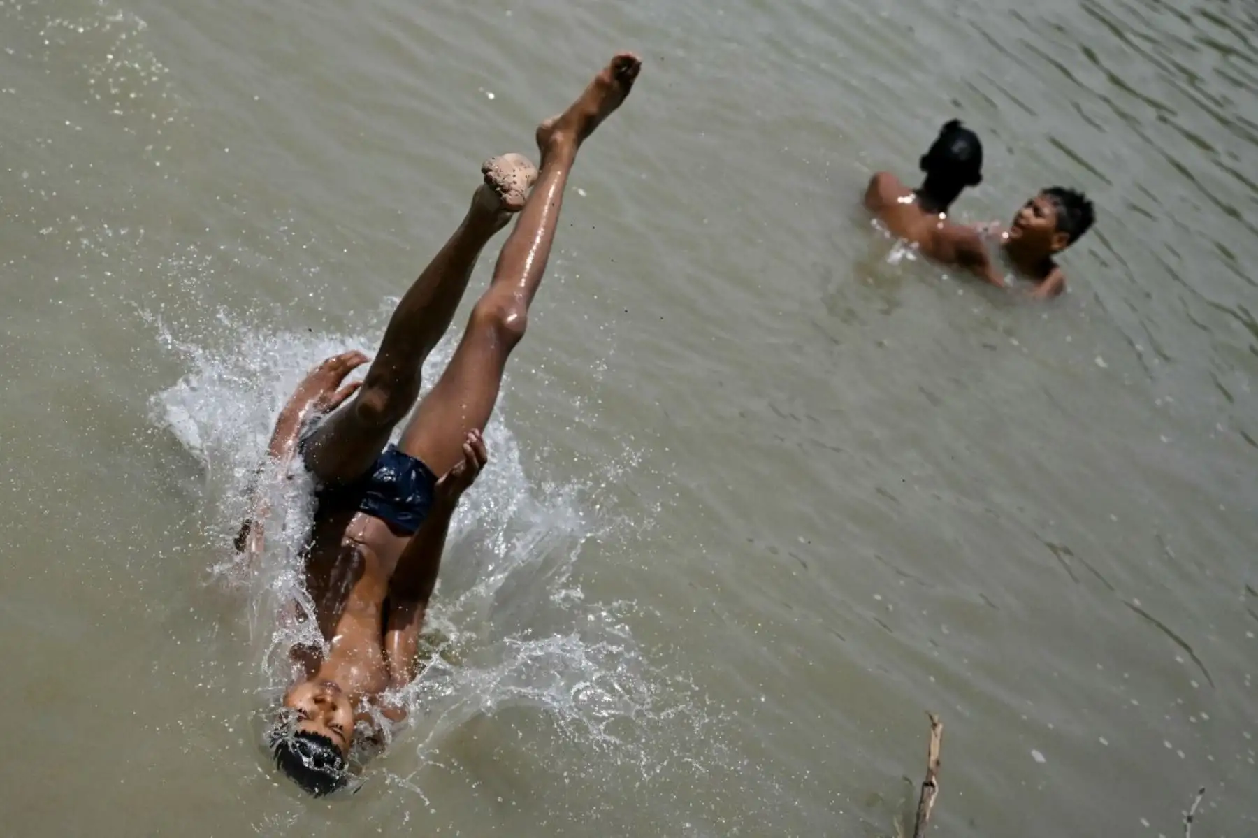 Un niño se sumerge en un lago para refrescarse en una calurosa tarde de verano en Nueva Delhi. Foto: AFP