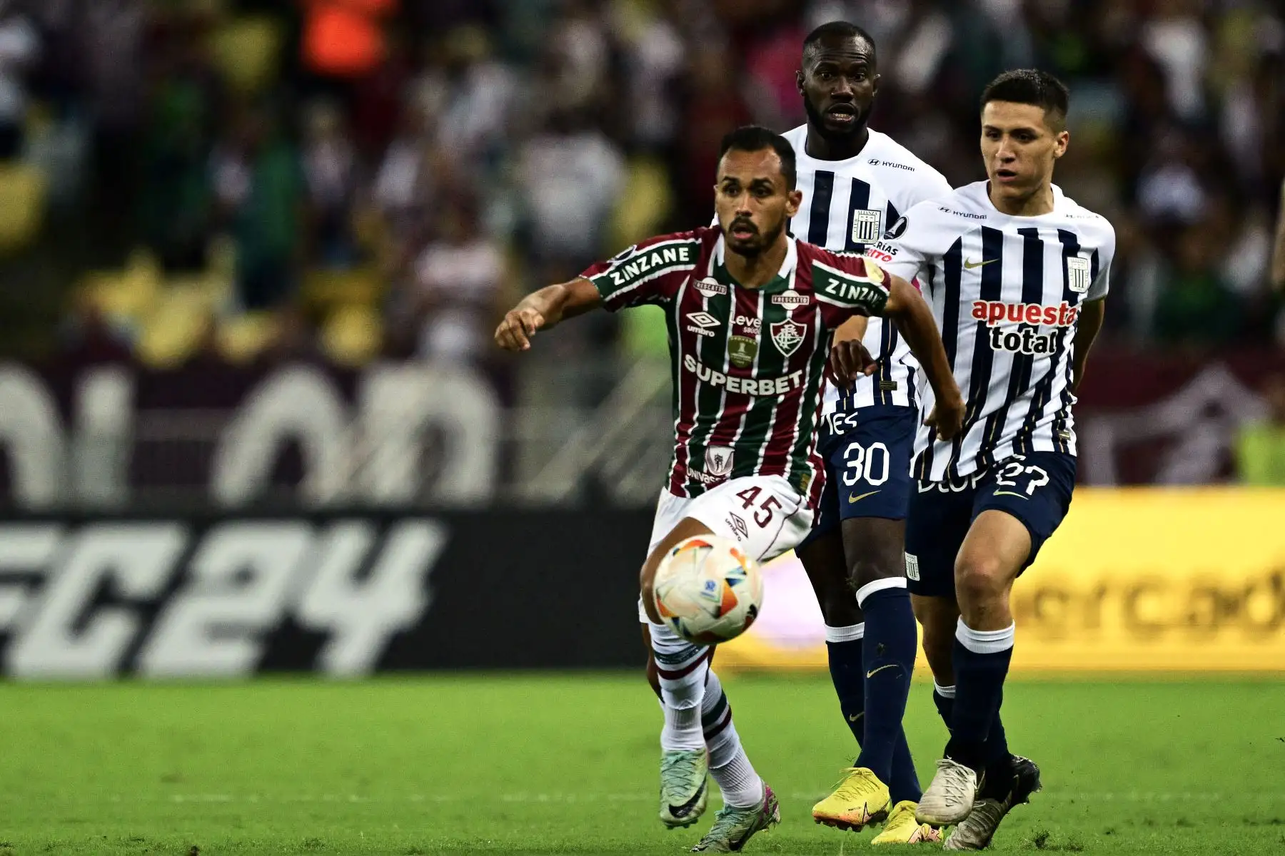El mediocampista de Fluminense Lima  mira el balón mientras corre frente al delantero panameño de Alianza Lima Cecilio Waterman  y el mediocampista de Alianza Lima Catriel Cabellos  durante el partido de fútbol de vuelta de la fase de grupos de la Copa Libertadores entre el Fluminense de Brasil y Alianza Lima de Perú. en el Estadio Maracaná de Río de Janeiro, Brasil.
Foto: AFP