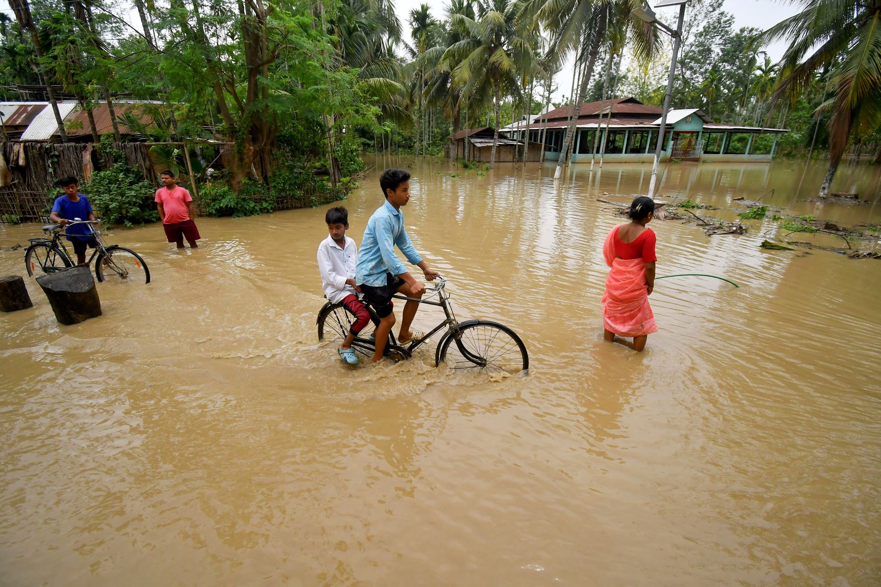 La gente avanza por una carretera inundada después de las fuertes lluvias en la aldea de Chang Chaki del distrito de Nagaon en el estado indio de Assam, tras la llegada a tierra del ciclón Remal en la India. Un poderoso ciclón que azotó las zonas bajas de Bangladesh e India mató al menos a 65 personas, incluidas tormentas de lluvia torrenciales a su paso. Foto: AFP