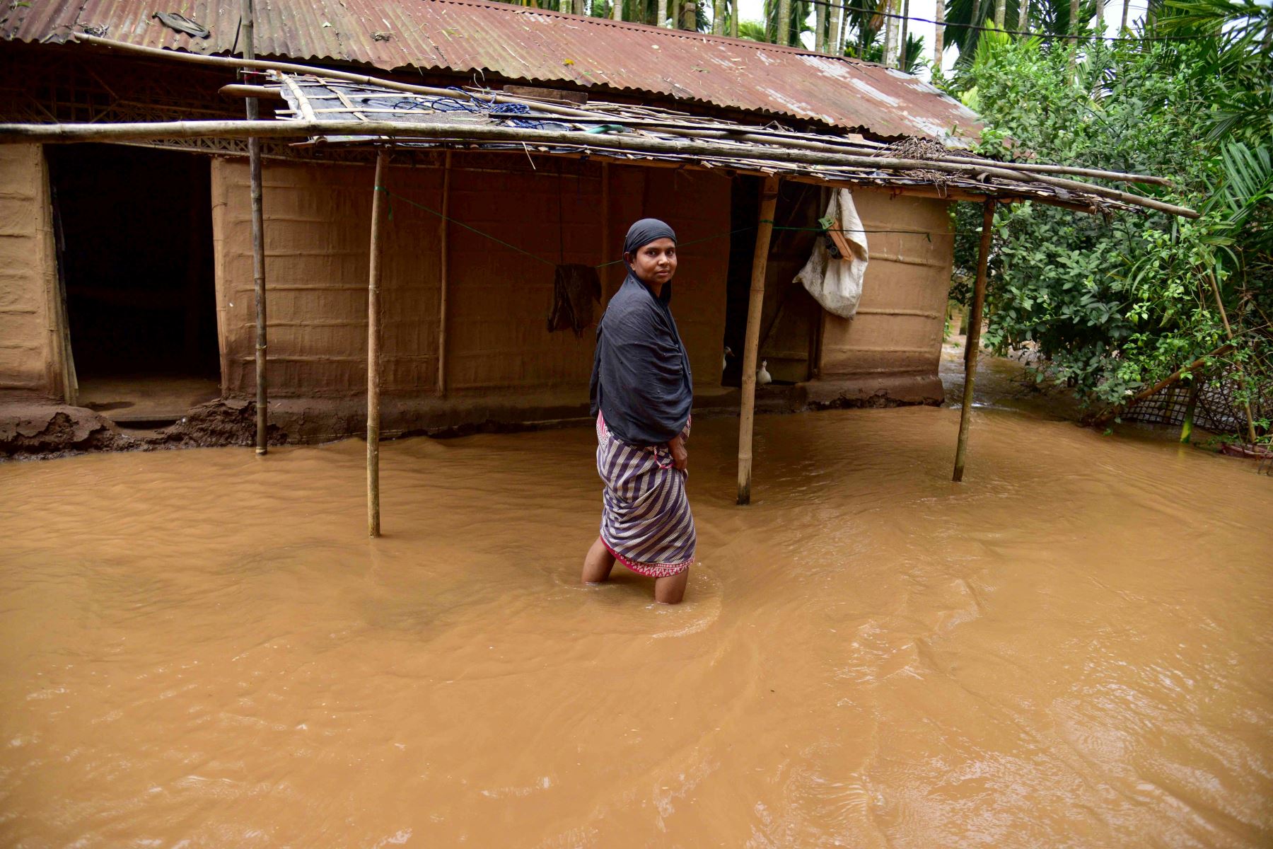 Una mujer camina por un patio inundado tras las fuertes lluvias tras la llegada del ciclón Remal a la aldea de Singi Mari del distrito de Nagaon, en el estado de Assam, La India. Foto: AFP