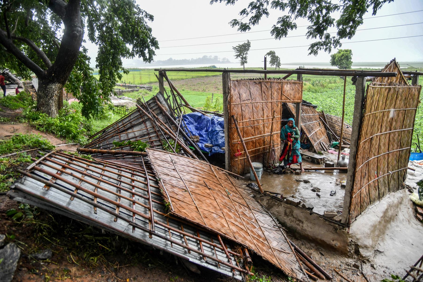 Una mujer recoge sus pertenencias de su casa destruida en la zona de Hatisila, en las afueras de Guwahati, tras la llegada del ciclón Remal a La India. Un poderoso ciclón que azotó las zonas bajas de Bangladesh e India mató al menos a 65 personas, incluidas tormentas de lluvia torrenciales a su paso. Foto: AFP