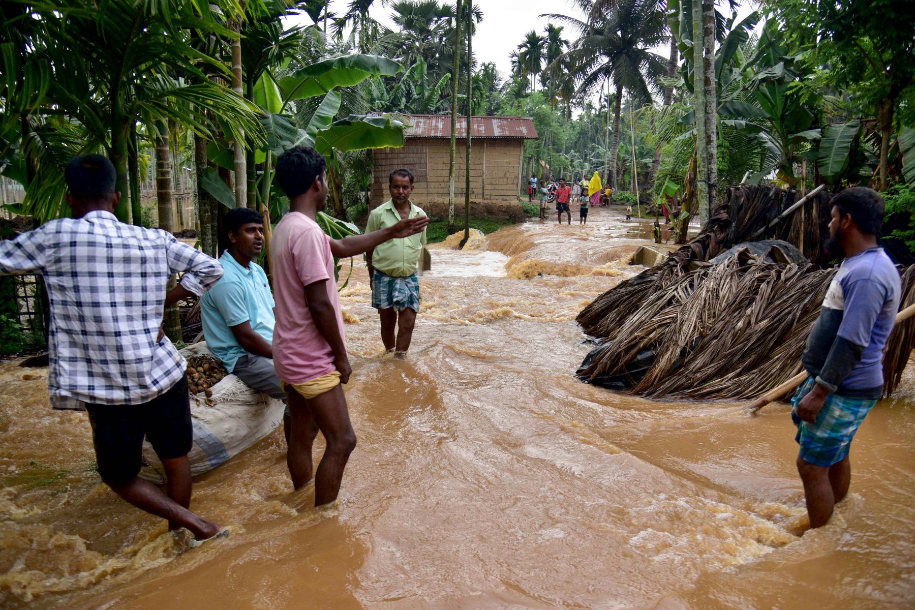 Los aldeanos caminan por una carretera inundada tras las fuertes lluvias tras la llegada del ciclón Remal a la aldea de Singi Mari del distrito de Nagaon, en el estado de Assam, La India. Foto: AFP