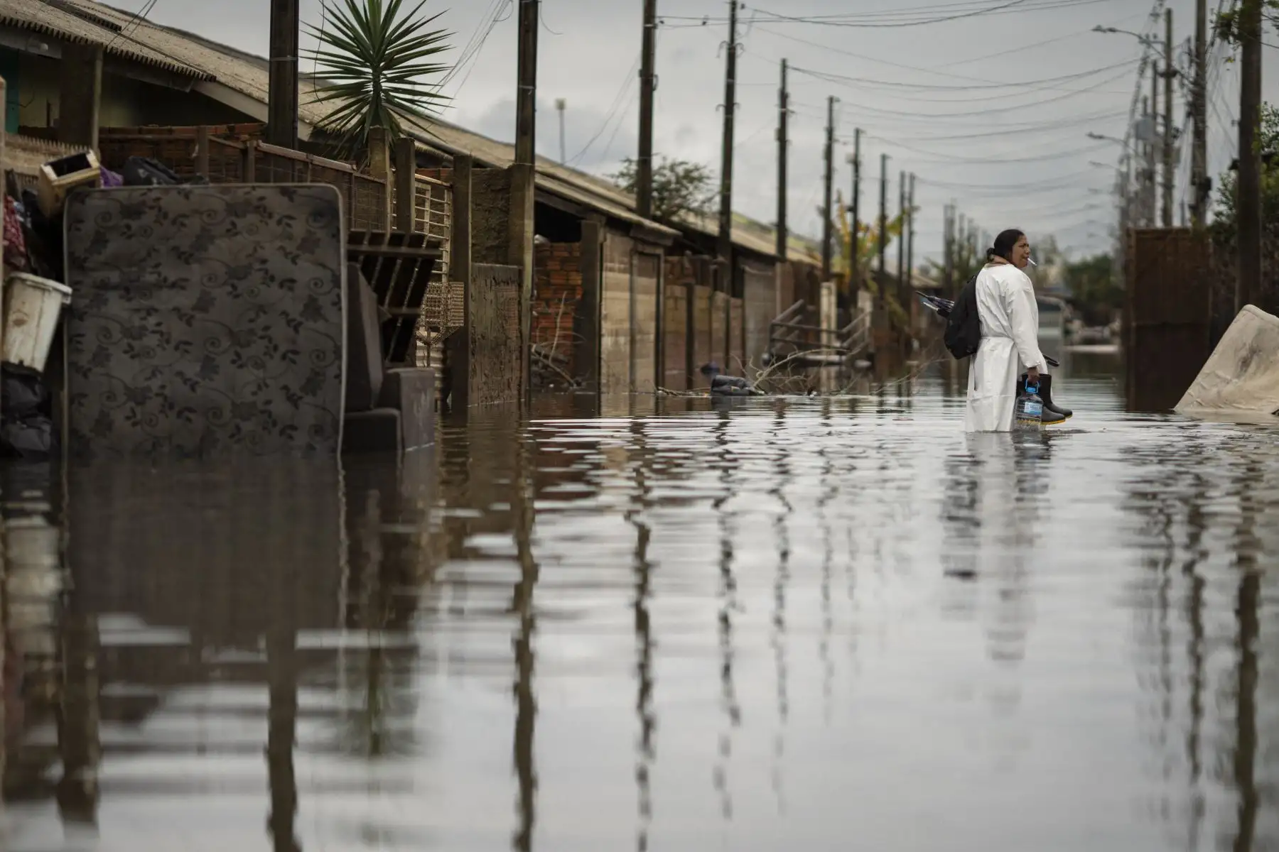 Vestida con un chubasquero blanco y unas botas de agua, Itajane Barbosa dos Santos, enfermera de 36 años, volvió este lunes a su casa en el barrio de Sarandi para empezar a limpiar. Foto: EFE