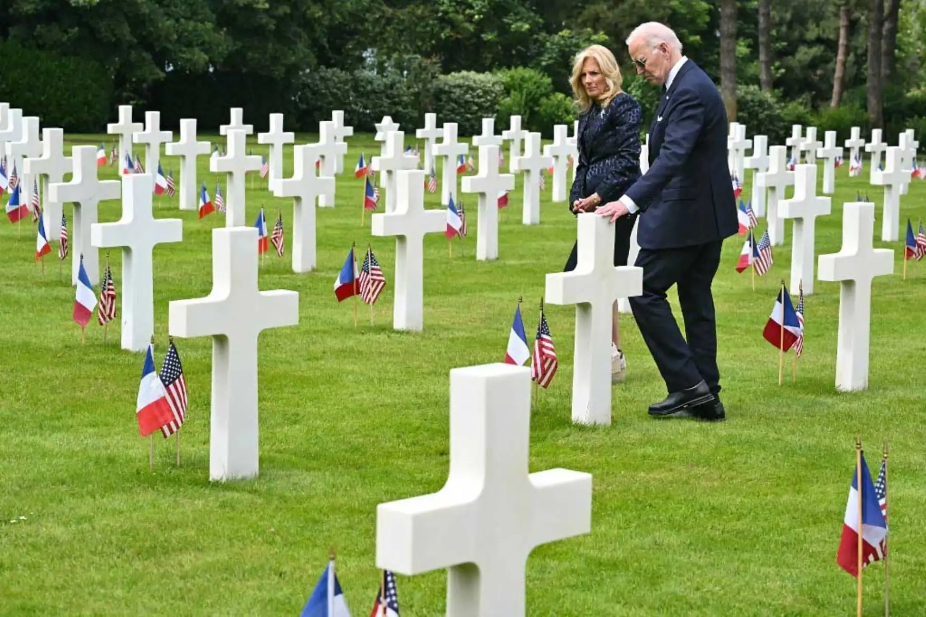 El presidente estadounidense Joe Biden saluda, flanqueado por la primera dama estadounidense Jill Biden, frente a una tumba en el cementerio y monumento conmemorativo estadounidense de Normandía después de la ceremonia estadounidense que conmemora el 80º aniversario del desembarco aliado del "Día D" de la Segunda Guerra Mundial en Normandía. Foto: AFP