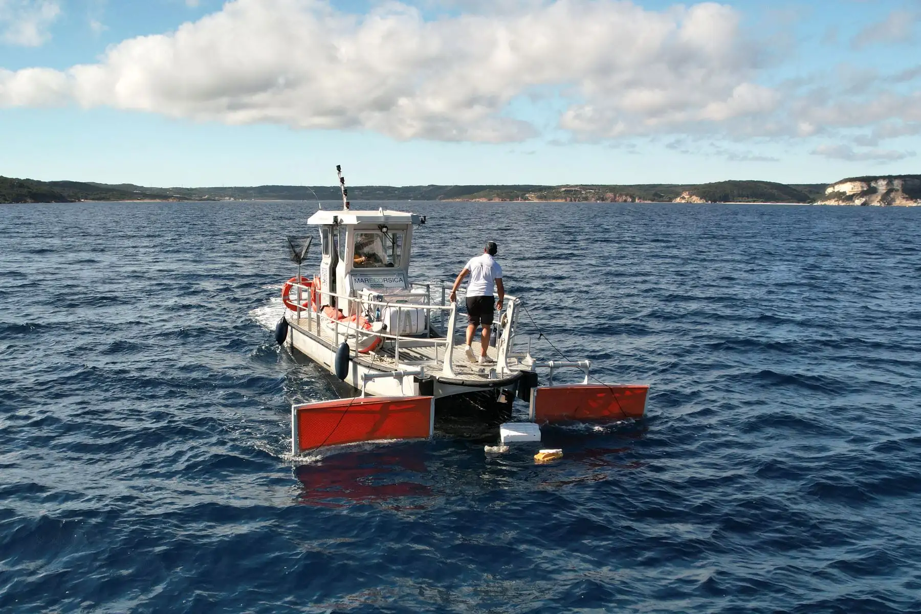 El barco capitán de Marecorsica, Bilal El Ouardani, navega mientras un innovador sistema de aspiración recoge grandes trozos de plástico, microplásticos y aceite por la parte delantera abierta del barco en el golfo de Sant