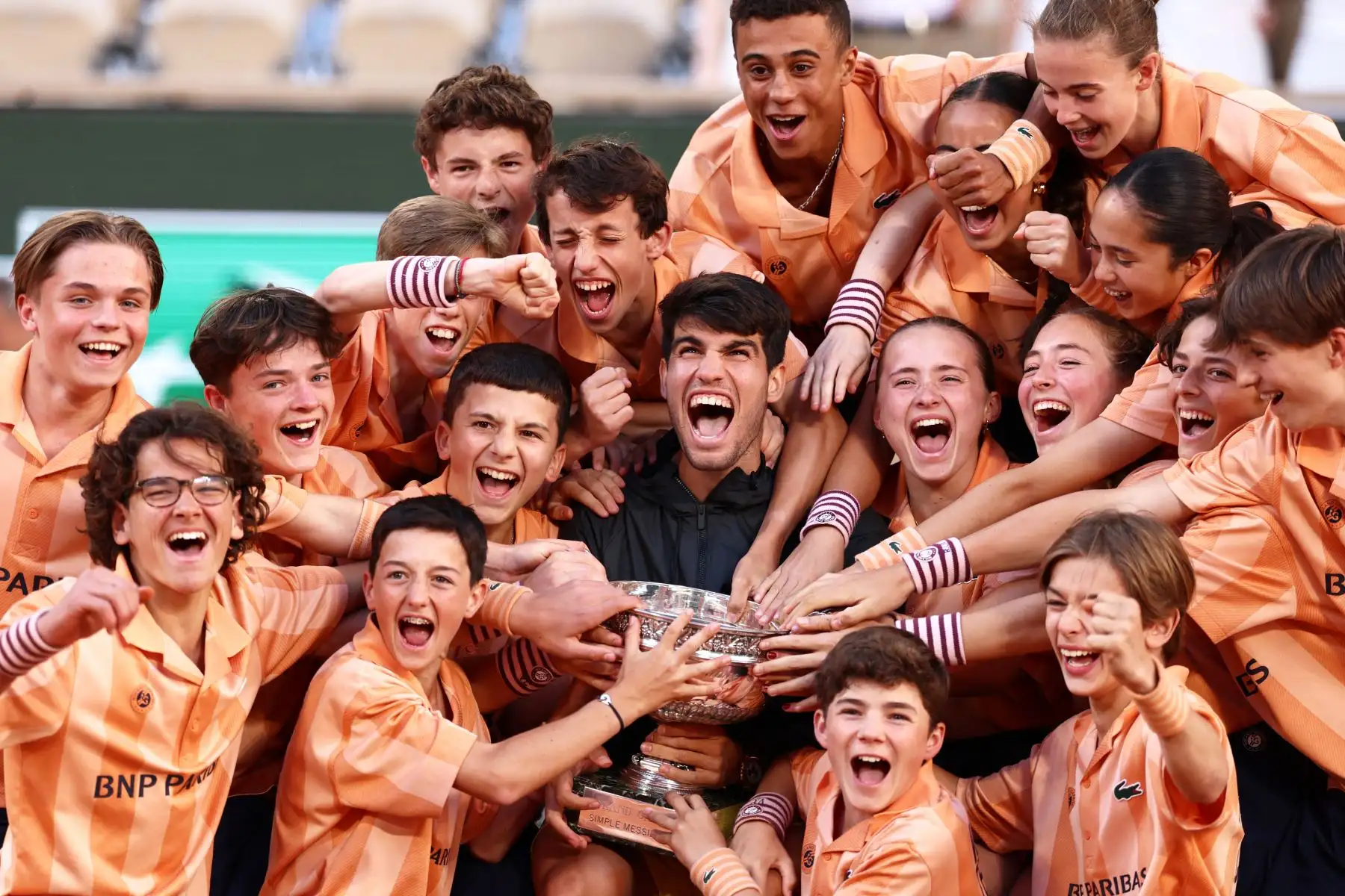 El español Carlos Alcaraz posa con recogepelotas y niñas después de ganar su partido final individual masculino contra el alemán Alexander Zverev en la cancha Philippe-Chatrier el día quince del torneo de tenis del Abierto de Francia. Foto: ANDINA/ AFP