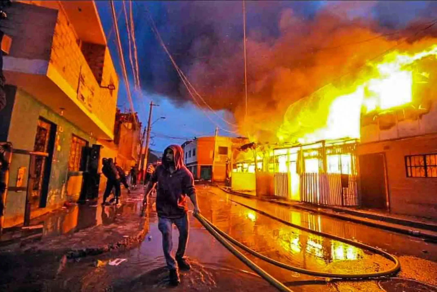 2019:  Vecino intenta ayudar a los bomberos ante el incendio que consumió una manzana entera en Corongo, Callao. Foto: Diego Vertiz