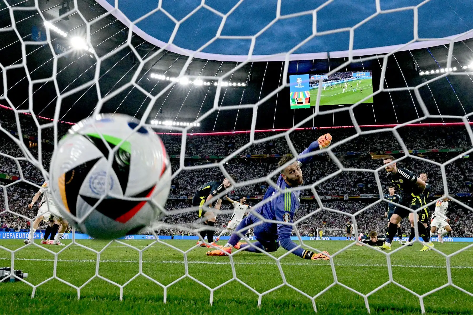 El centrocampista alemán #10 Jamal Musiala (R) anota el segundo gol de su equipo ante el portero escocés #01 Angus Gunn durante el partido de fútbol del Grupo A de la UEFA Euro 2024 entre Alemania y Escocia en el Munich Football Arena de Munich el 14 de junio de 2024. Foto: AFP