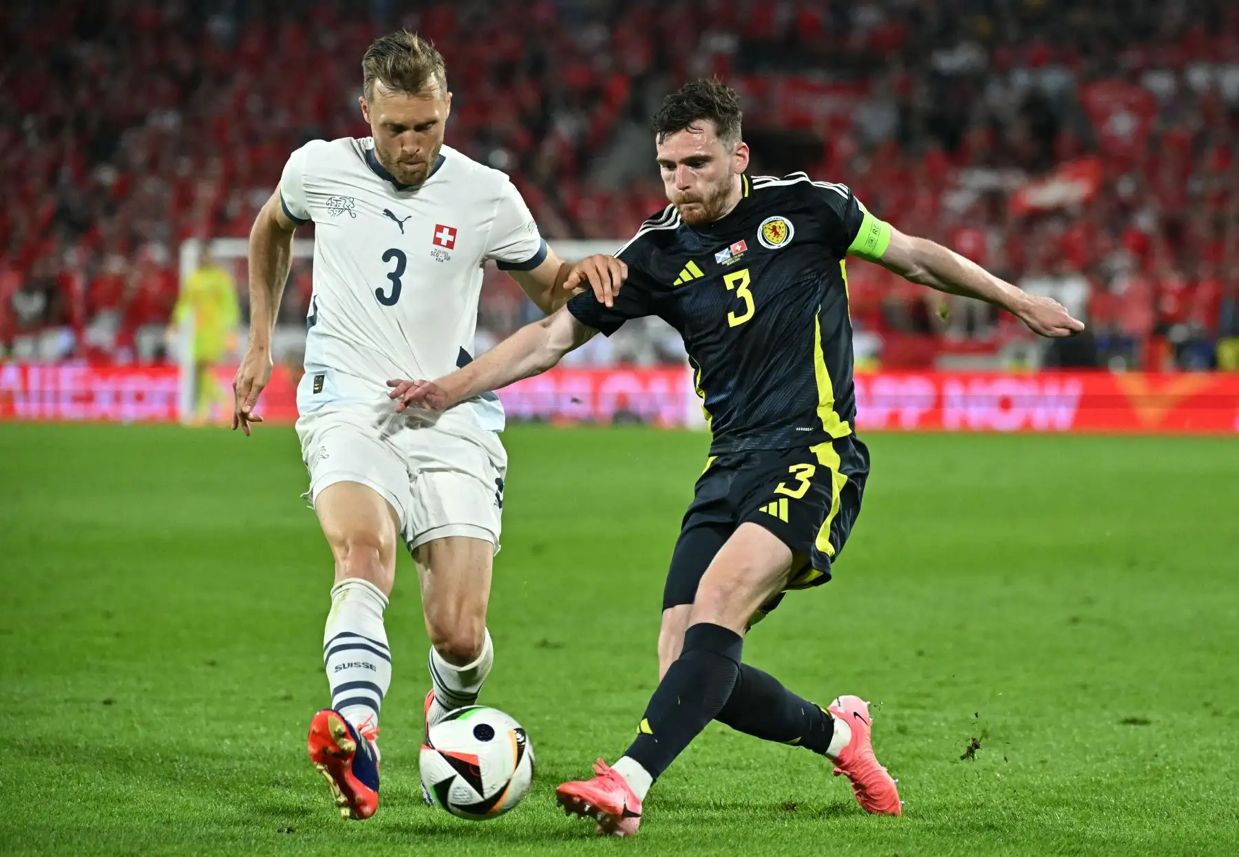 El defensor de Escocia Andrew Robertson lucha por el balón con el defensor de Suiza Silvan Widmer durante el partido de fútbol del grupo A de la UEFA Euro 2024 entre Escocia y Suiza en el estadio de Colonia. Foto: ANDINA/AFP
