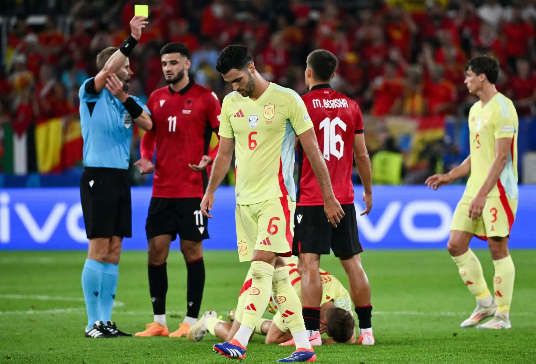 El árbitro sueco Glenn Nyberg  muestra una tarjeta amarilla al delantero de Albania Medon Berisha mientras el centrocampista español #06 Mikel Merino mira durante el partido de fútbol del Grupo B de la UEFA Euro 2024 entre Albania y España en el Duesseldorf Arena. Foto: ANDINA/ AFP