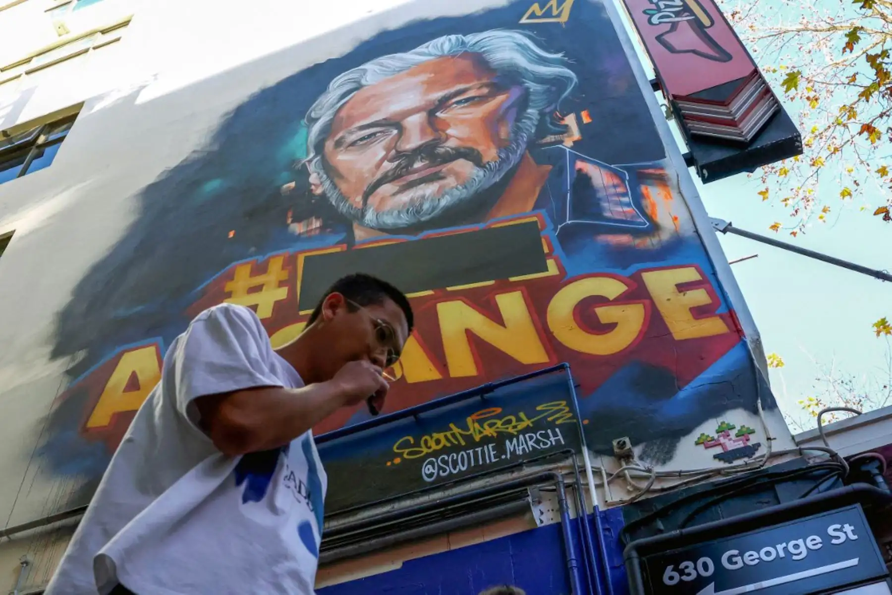 Un turista camina debajo de un mural del fundador de Wikileaks, Julian Assange, en Melbourne el 25 de junio de 2024. Foto: AFP