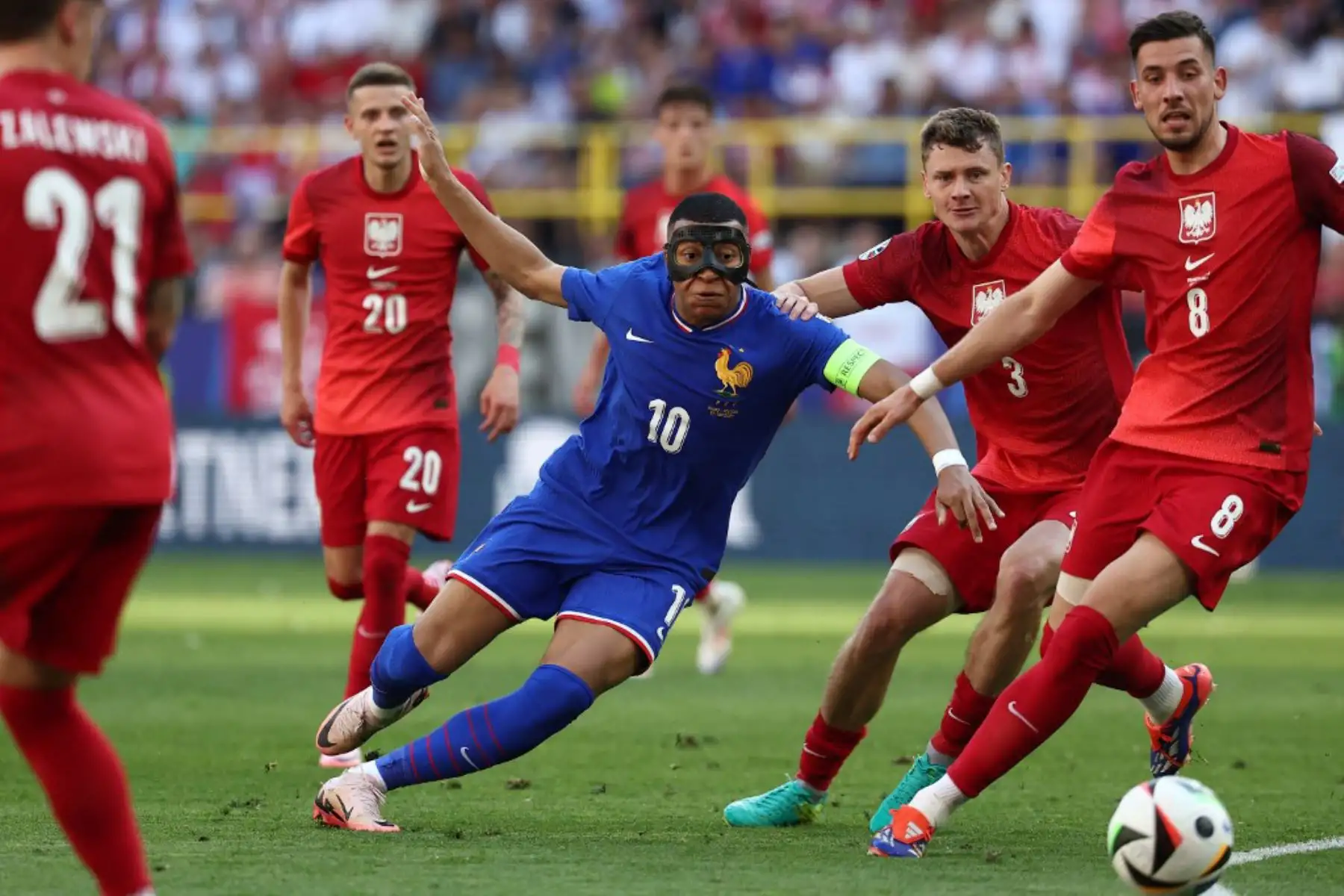 El delantero francés Kylian Mbappe, con una máscara protectora,luch a por el balón con el centrocampista polaco Sebastian Szymanski, el centrocampista polaco Pawel Dawidowicz y el centrocampista polaco Jakub Moder durante la Eurocopa Partido de fútbol del Grupo D de 2024 entre Francia y Polonia en el BVB Stadion de Dortmund. Foto: AFP