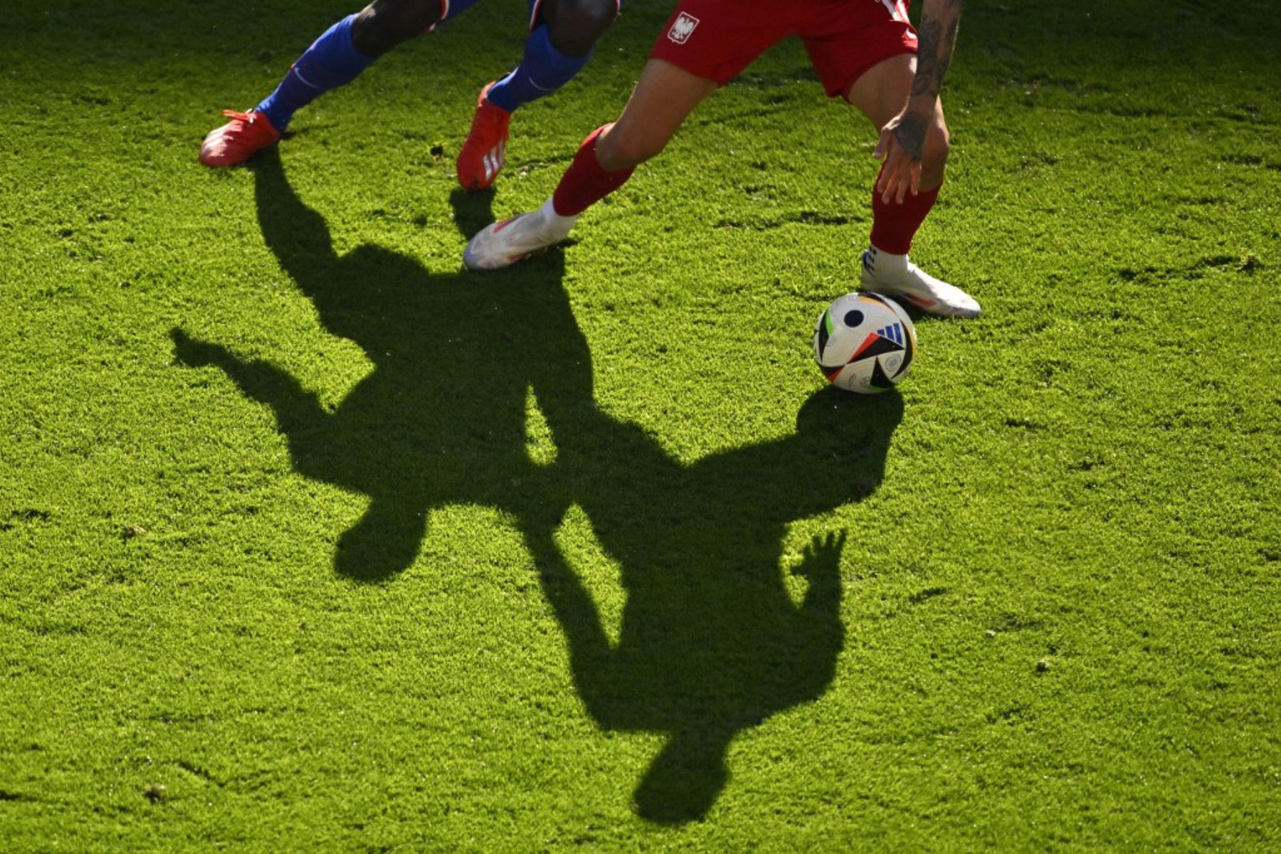 Las sombras de los jugadores se proyectan en el campo mientras compiten por el balón durante el partido de fútbol del Grupo D de la UEFA Euro 2024 entre Francia y Polonia en el BVB Stadion de Dortmund. Foto: AFP