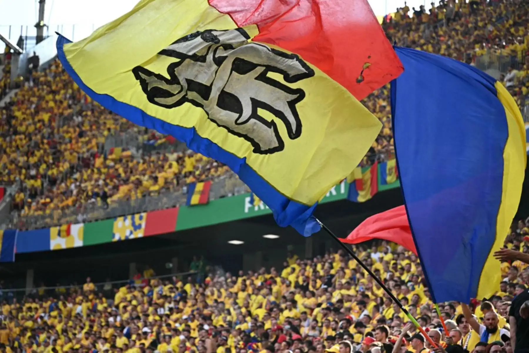Aficionados rumanos enarbolan grandes banderas  mientras esperan el inicio del partido entre Eslovaquia y Rumanía por el Grupo E de la UEFA Euro 2024  en el Frankfurt Arena el 26 de junio de 2024. Foto: AFP