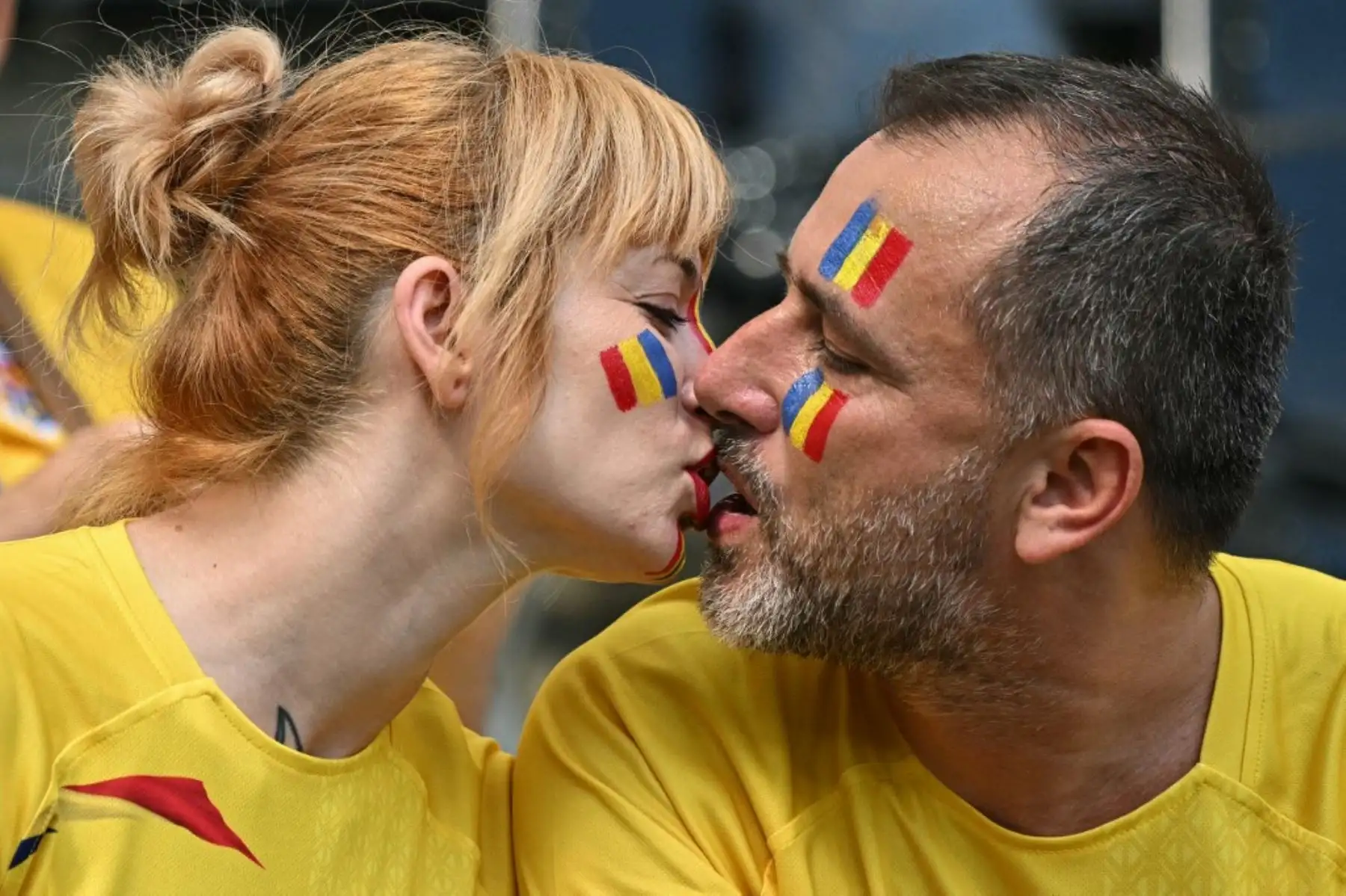 Una pareja de rumanos se besan en el Frankfurt Arena mientras esperan el inicio del partido entre Eslovaquia y Rumanía por el Grupo E de la UEFA Euro 2024  el 26 de junio de 2024. Foto: AFP