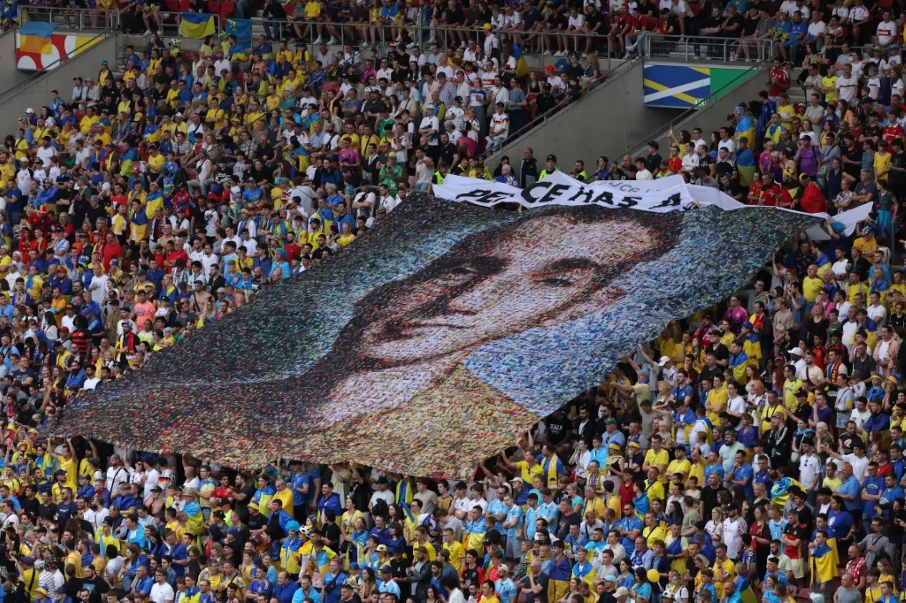 Hinchas ucranianos agitan una pancarta con el retrato del soldado caído Nazariy Hryntsevich y el lema "La paz tiene un precio", durante el partido de fútbol del Grupo E de la UEFA Euro 2024 entre Ucrania y Bélgica en el Stuttgart Arena el 26 de junio de 2024. Foto: AFP