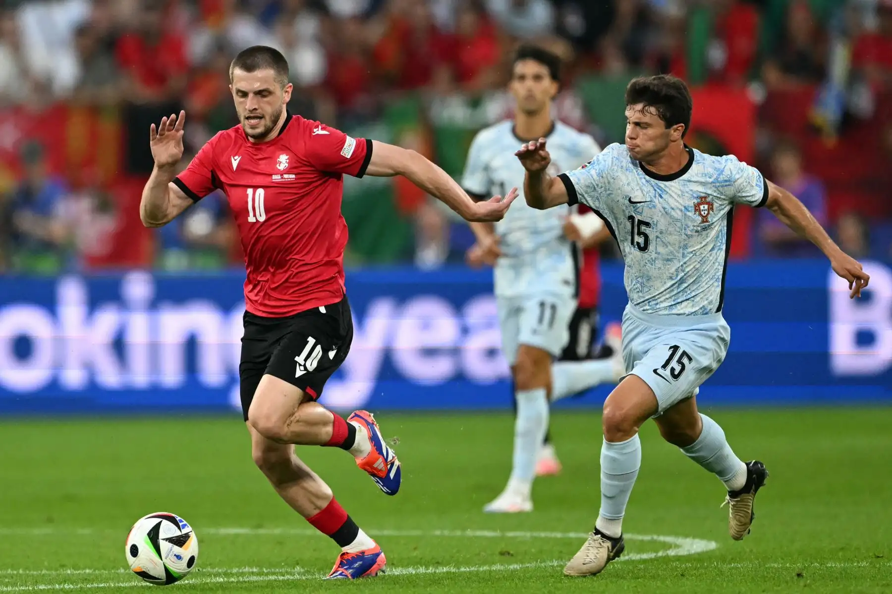 El centrocampista de Georgia Giorgi Chakvetadze y el centrocampista de Portugal Joao Neves compiten por el balón durante el partido de fútbol del Grupo F de la UEFA Euro 2024 entre Georgia y Portugal. Foto: ANDINA/AFP