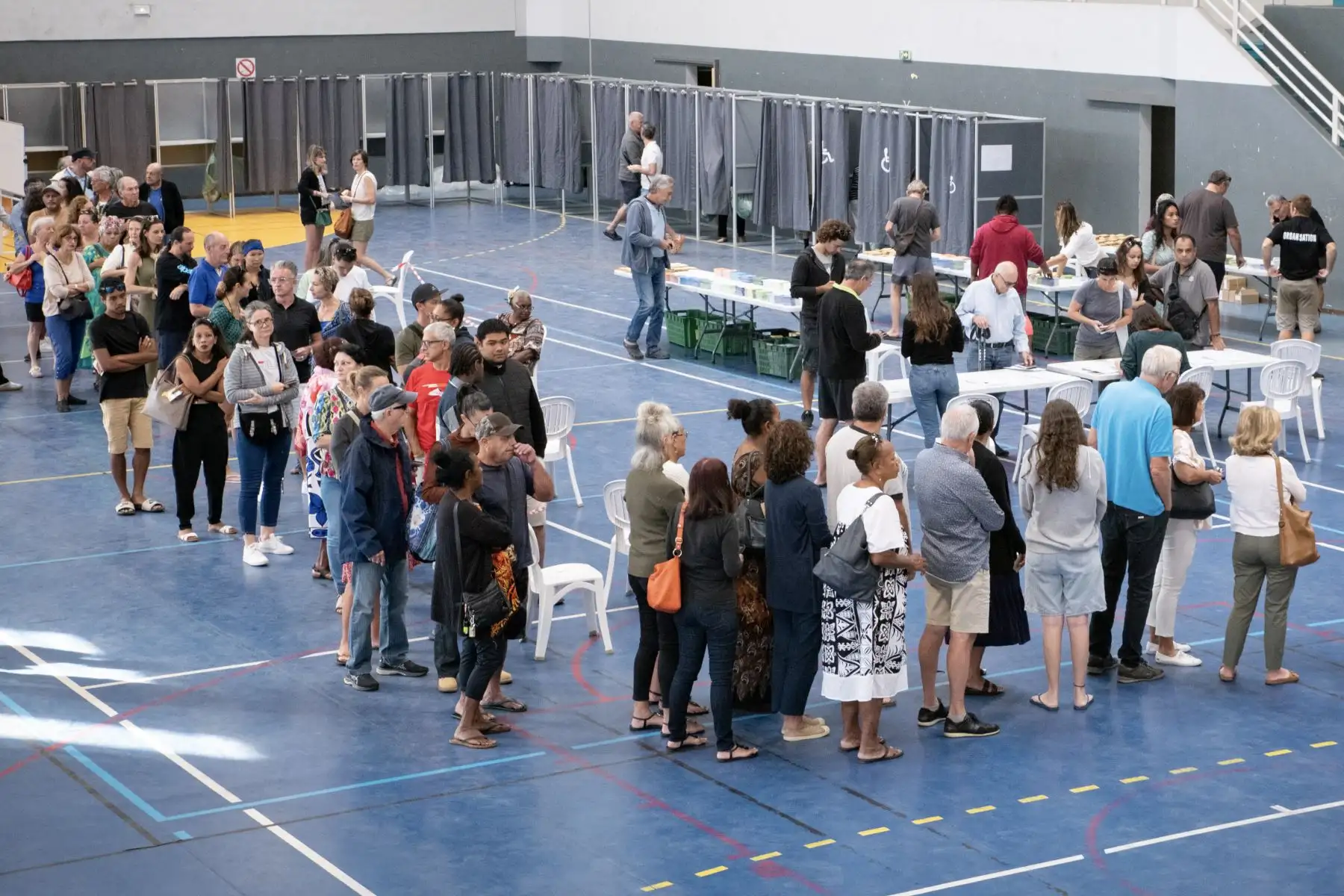 La gente hace cola frente a los colegios electorales dentro del pabellón deportivo Anse Vata para votar en la primera ronda de las cruciales elecciones legislativas de Francia en Noumea, en Francia. AFP