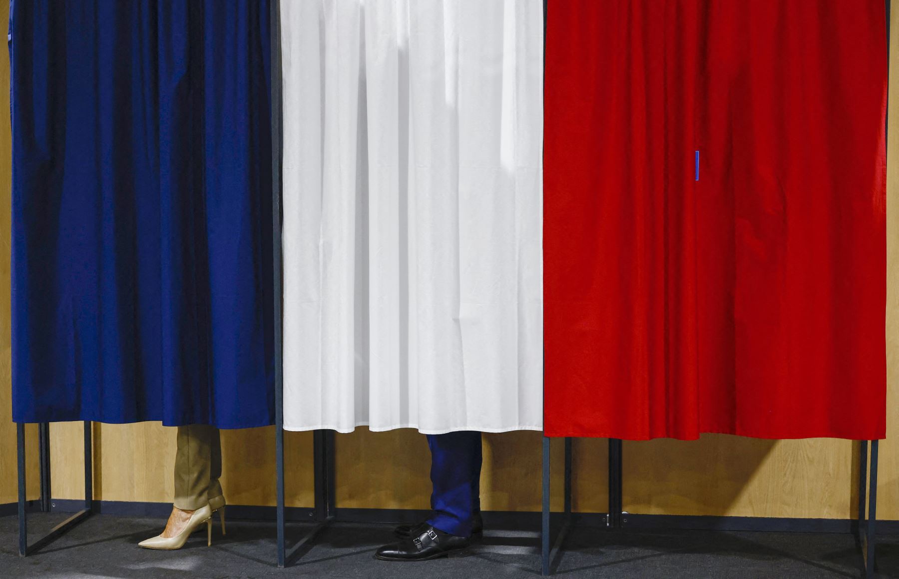 Emmanuel Macron y su esposa Brigitte Macron se encuentran en la cabina electoral antes de votar en la primera vuelta de las elecciones parlamentarias en un colegio electoral en Le Touque. AFP