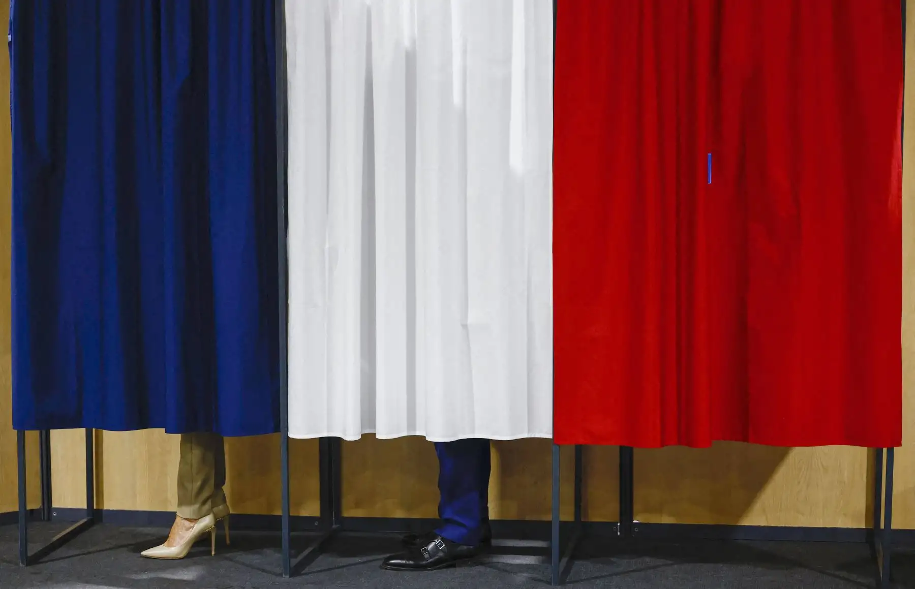 Emmanuel Macron y su esposa Brigitte Macron se encuentran en la cabina electoral antes de votar en la primera vuelta de las elecciones parlamentarias en un colegio electoral en Le Touque. AFP