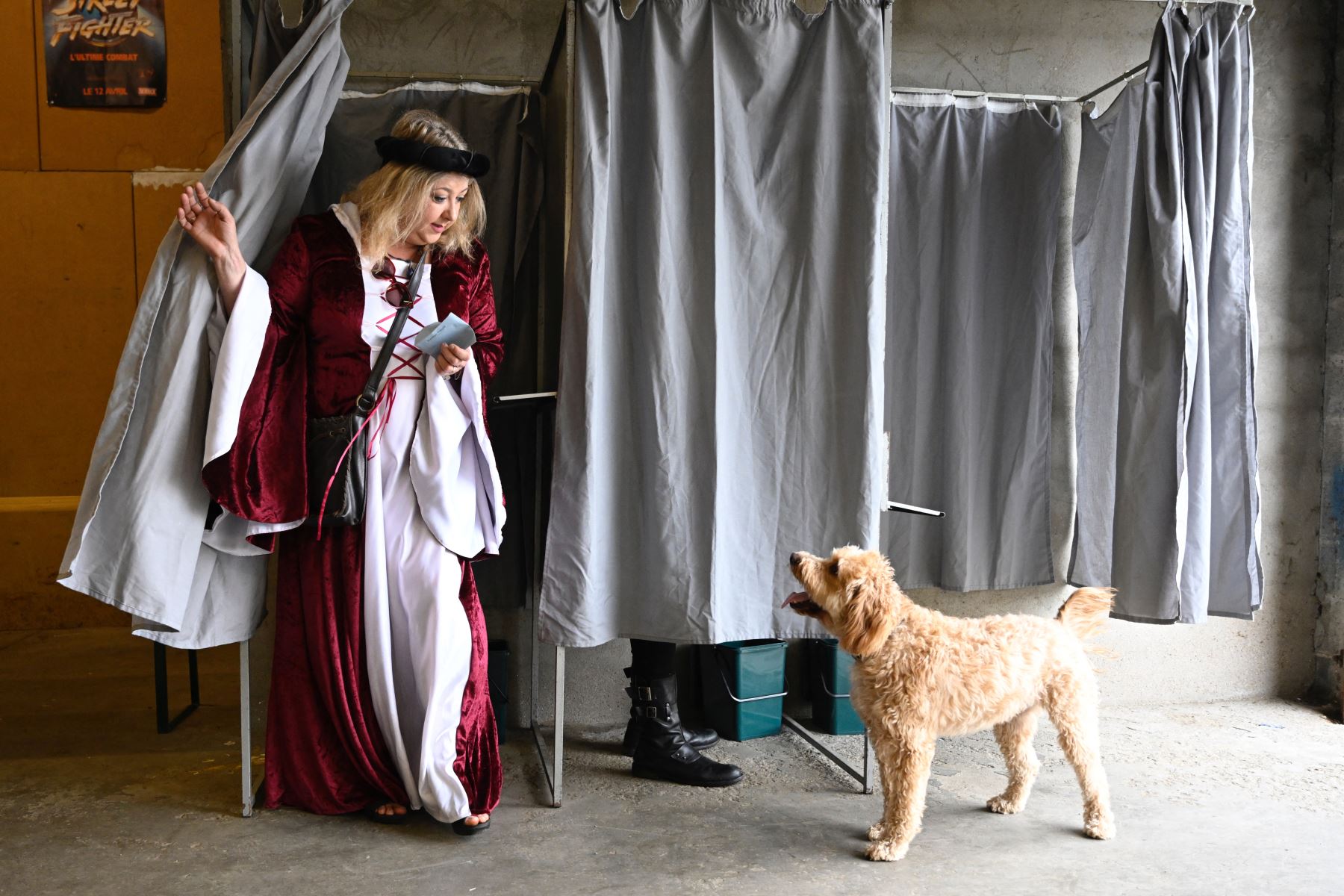 Un votante con traje medieval saluda a un perro cuando sale de la cabina electoral. AFP