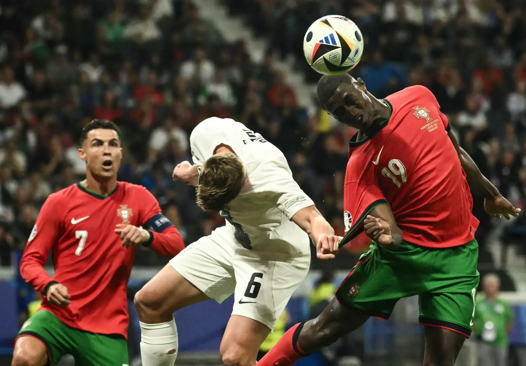 El defensor de Portugal, Nuno Mendes, cabecea el balón pasando al defensor de Eslovenia, Jaka Bijol, mientras el delantero de Portugal, Cristiano Ronaldo, observa durante el partido de octavos de final de la UEFA Euro 2024 entre Portugal y Eslovenia en el Frankfurt Arena de Frankfurt am Main el 1 de julio. 2024. Foto: AFP