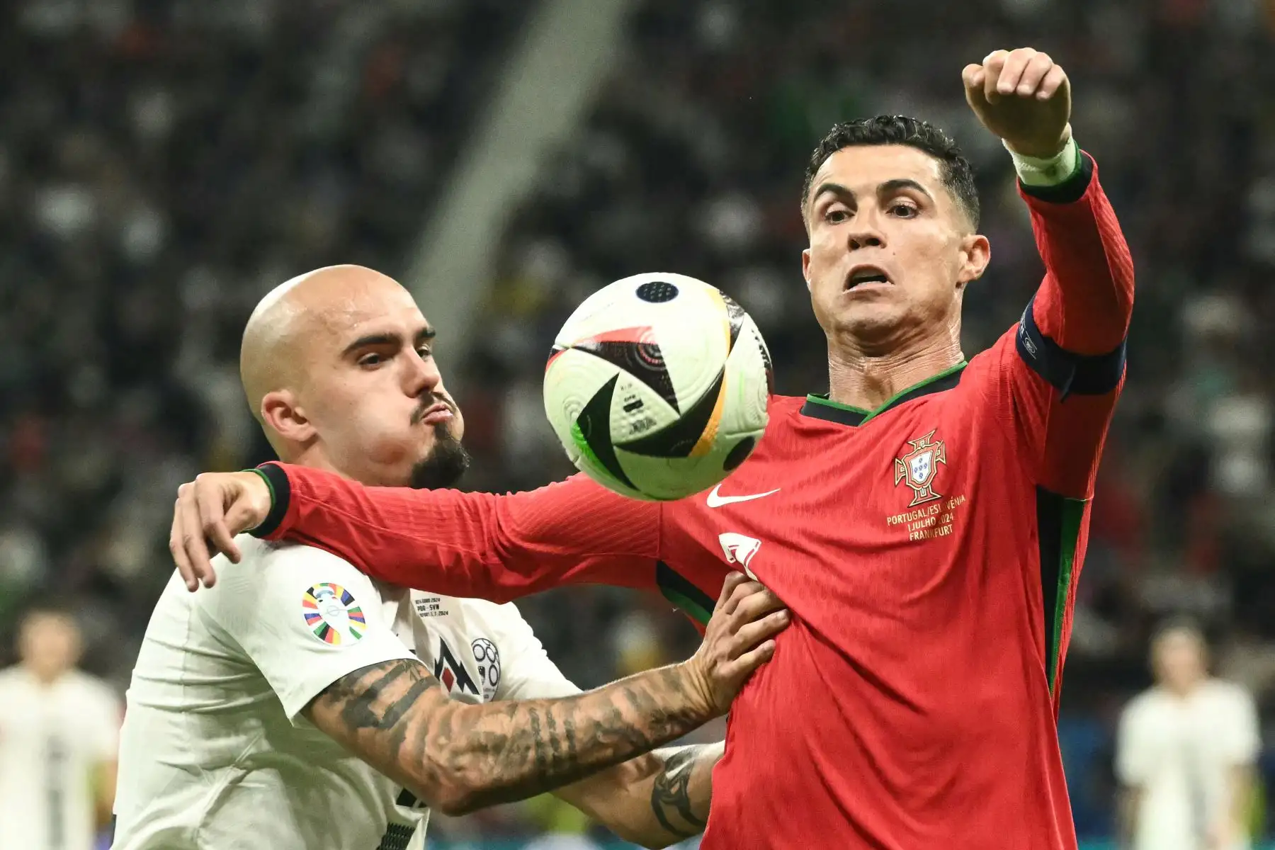 La defensa eslovena Vanja Drkusic lucha por el balón con el delantero portugués Cristiano Ronaldo durante el partido de octavos de final de la UEFA Euro 2024 entre Portugal y Eslovenia en el Frankfurt Arena de Frankfurt am Main el 1 de julio de 2024. Foto: AFP