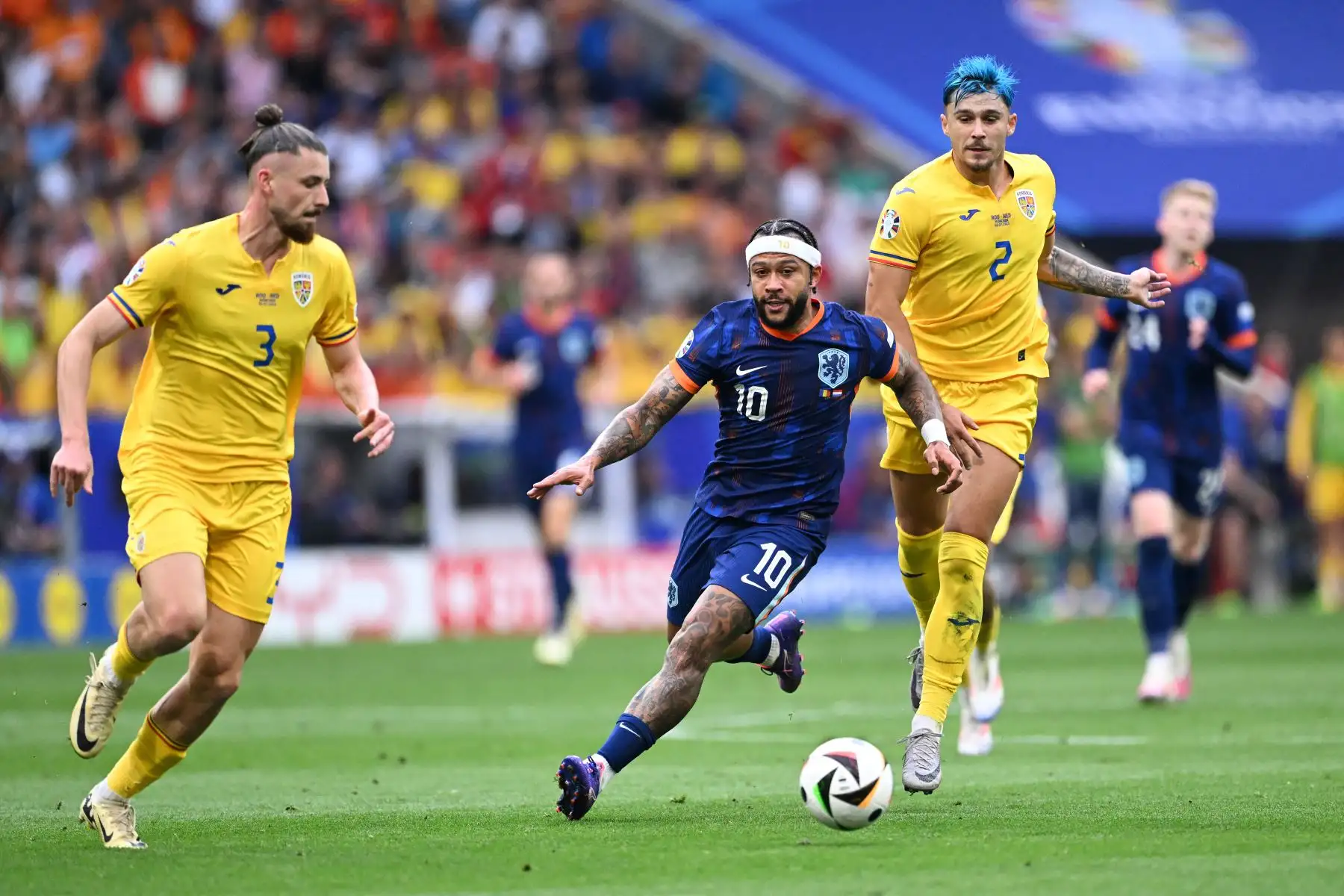 El delantero holandés Memphis Depay corre con el balón perseguido por el defensor rumano Radu Dragusin  y el defensor rumano  Andrei Ratiu durante el partido de fútbol de octavos de final de la UEFA Euro 2024 entre Rumania y Holanda en el Munich Football Arena.
Foto: AFP