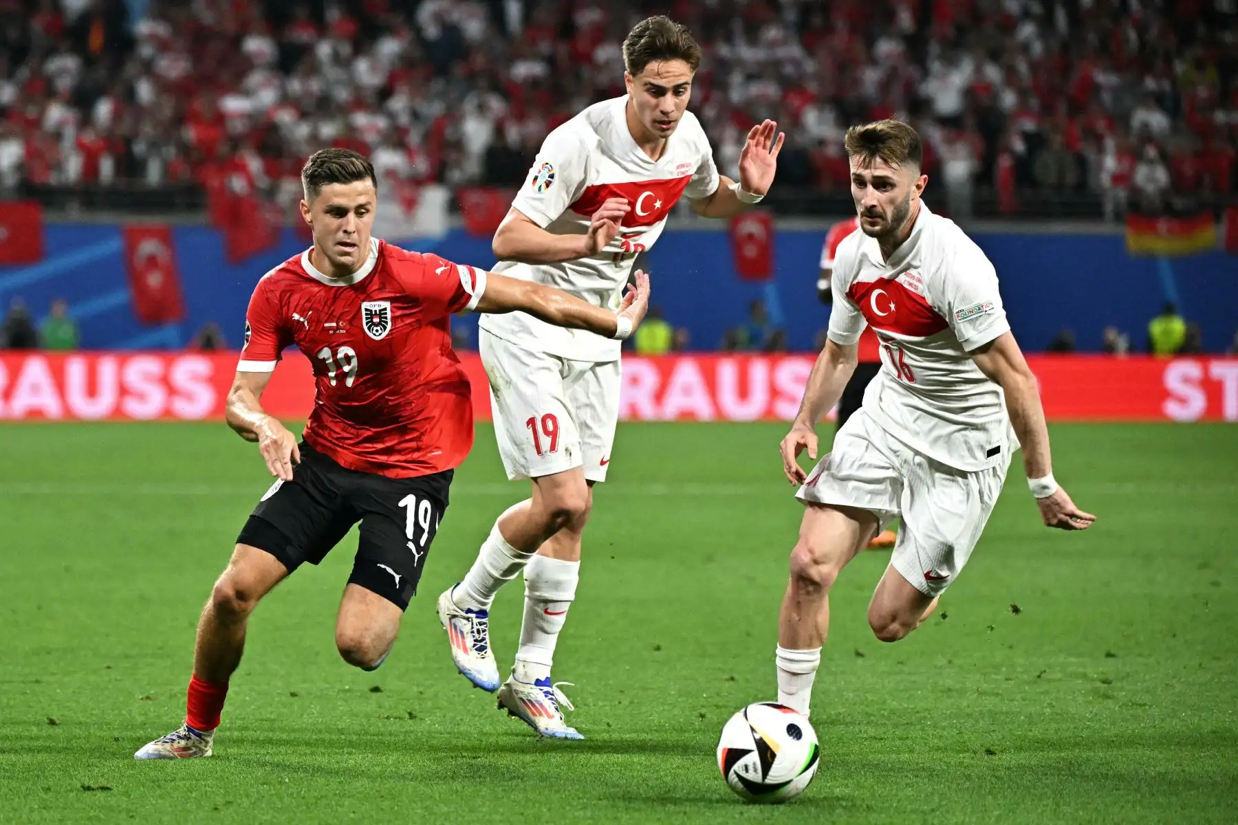 El centrocampista de Austria Christoph Baumgartner lucha por el balón con el mediocampista de Turquía Ismail Yuksek  y el delantero de Turquía  Kenan Yildiz  durante el partido de fútbol de octavos de final de la UEFA Euro 2024 entre Austria y Turquía. Foto: ANDINA/ AFP