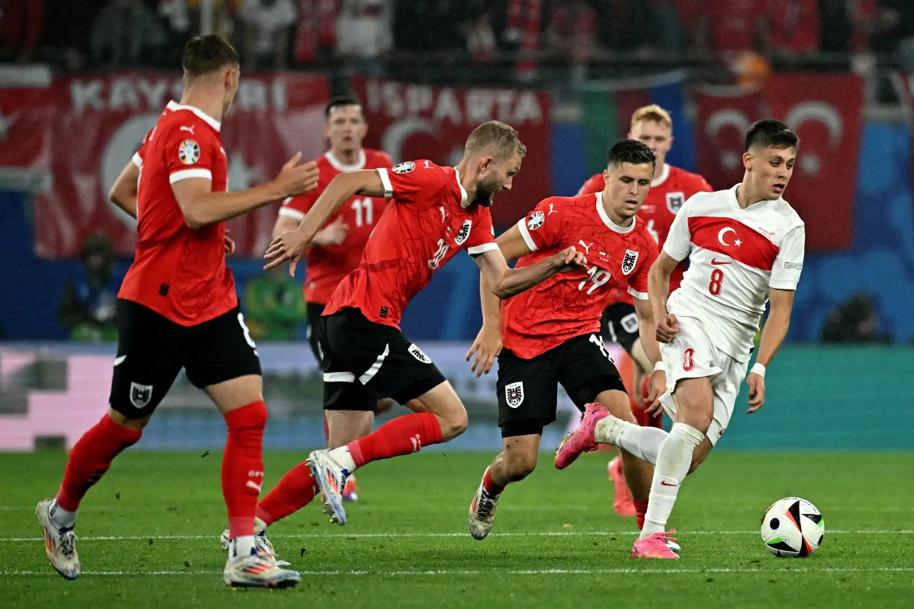 El delantero de Turquía Arda Guler lucha por el balón con el centrocampista de Austria Konrad Laimer  y el centrocampista de Austria Christoph Baumgartner (2do R) durante el partido de fútbol de octavos de final de la UEFA Euro 2024 entre Austria y Turquía. Foto: ANDINA/AFP