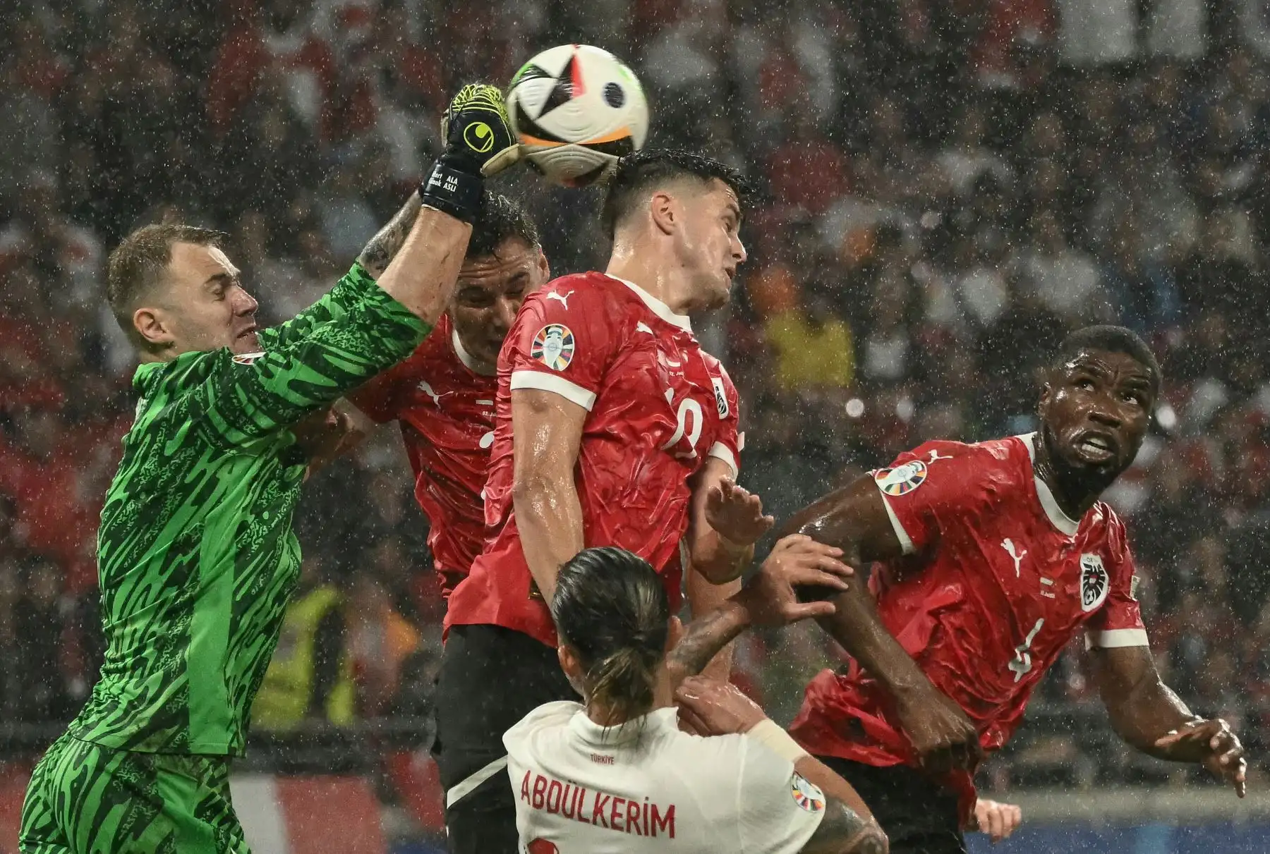 El portero de Turquía  Mert Gunok golpea el balón junto al defensor de Austria  Kevin Danso y el centrocampista de Austria Christoph Baumgartner  durante el partido de fútbol de octavos de final de la UEFA Euro 2024 entre Austria y Turquía. Foto: ANDINA/AFP