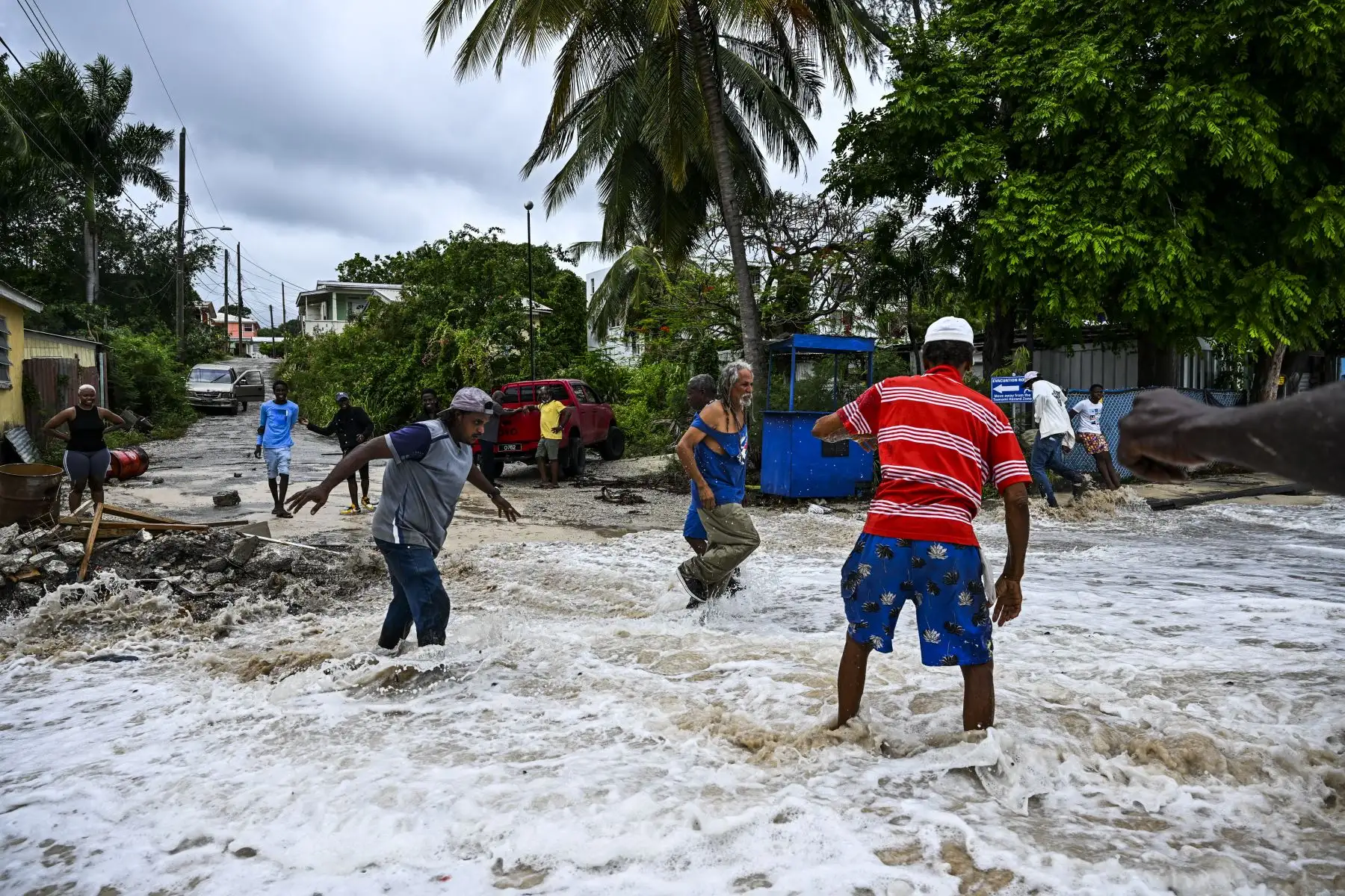 La gente camina entre las inundaciones causadas por el agua de mar después del paso del huracán Beryl en la parroquia de Saint James, Barbados. Según los reportes de las autoridades en la región, el fenómeno dejó al menos tres muertos en Granada, uno en San Vicente y las Granadinas y uno en la costa de Venezuela. Foto: AFP