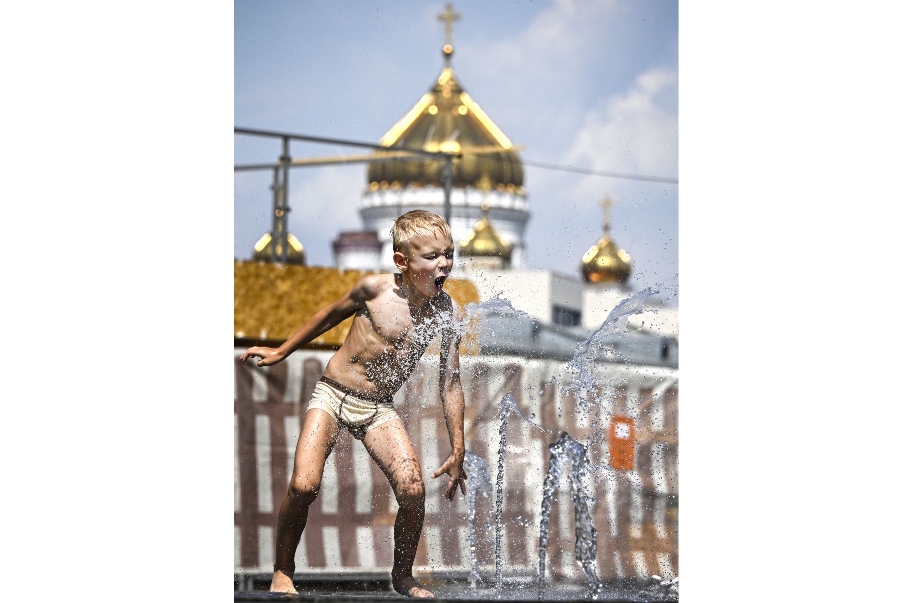 Un niño juega en una fuente durante el calor del mediodía frente a la catedral de Cristo Salvador en el centro de Moscú. La Agencia Meteorológica Rusa ha ampliado una alerta meteorológica naranja por un calor récord en la capital rusa y la región de Moscú. 
Foto: AFP