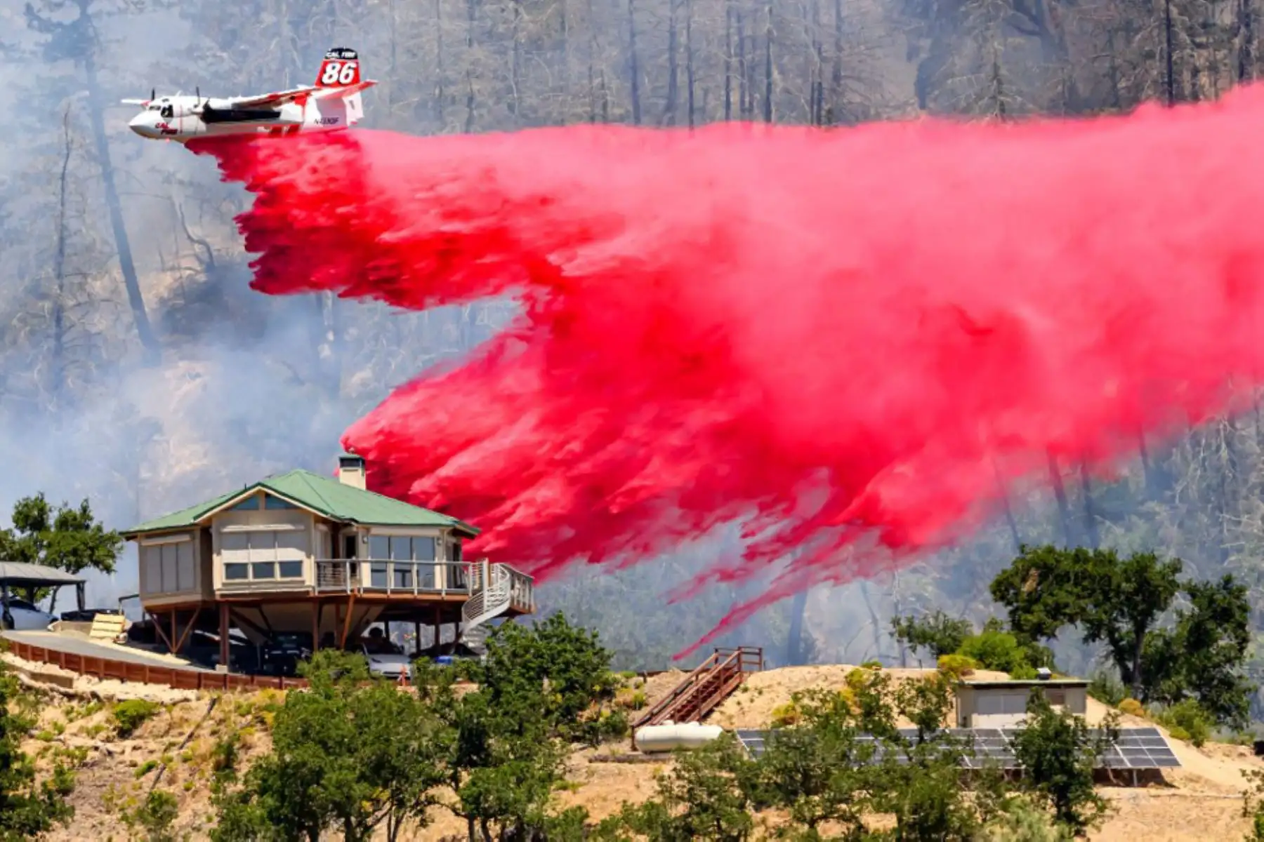 Un avión cisterna arroja retardante de fuego sobre una casa durante el incendio de Toll en Calistoga, California. Una ola de calor está elevando las temperaturas, lo que ha provocado advertencias de incendio con bandera roja en todo el estado.Foto: AFP