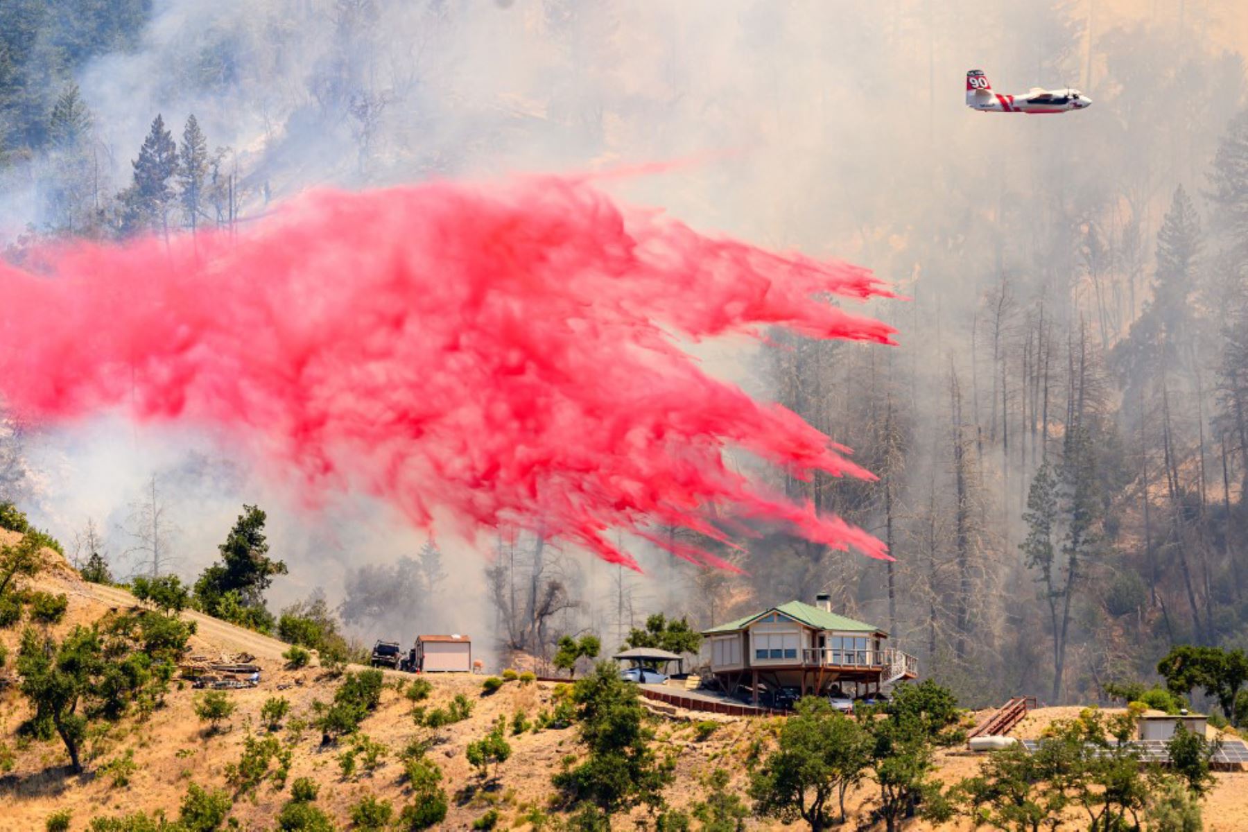 Un avión cisterna arroja retardante de fuego sobre una casa durante el incendio de Toll en Calistoga, California. Una ola de calor está elevando las temperaturas, lo que ha provocado advertencias de incendio con bandera roja en todo el estado.Foto: AFP