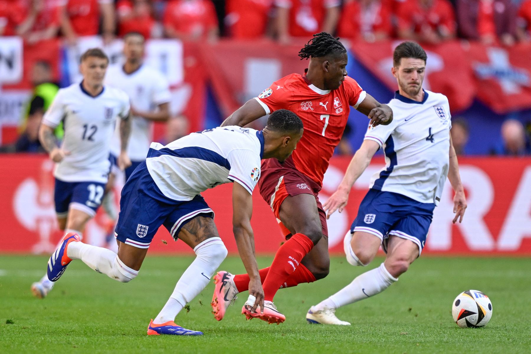 El defensor de Inglaterra  Ezri Konsa, el delantero de Suiza  Breel Embolo y el mediocampista de Inglaterra  Declan Rice luchan por el balón durante el partido de fútbol de cuartos de final de la UEFA Euro 2024 entre Inglaterra y Suiza. AFP