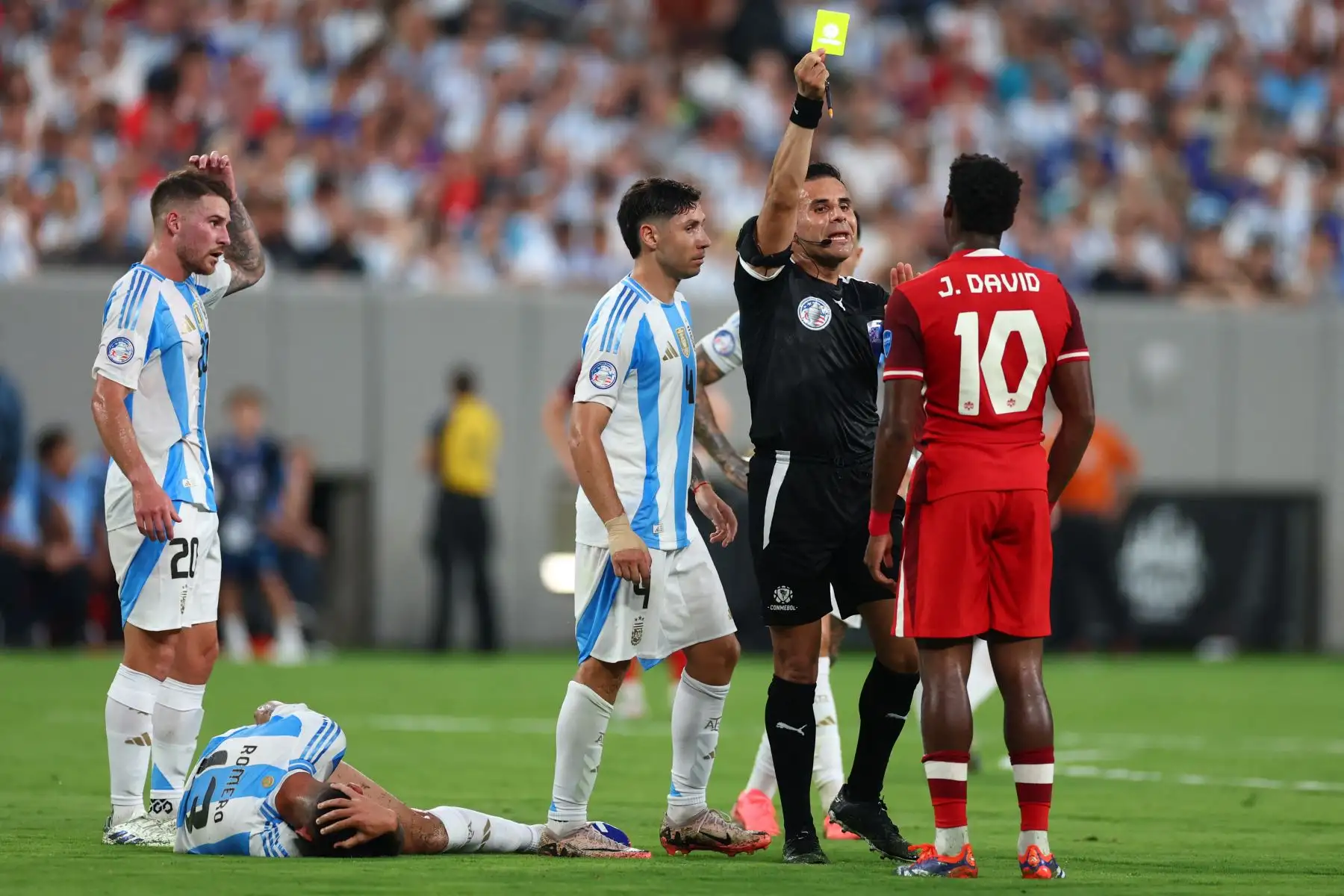 El árbitro Piero Maza muestra una tarjeta amarilla a Jonathan David de Canadá durante el partido semifinal de la CONMEBOL Copa América 2024 entre Canadá y Argentina. Foto: ANDINA/AFP