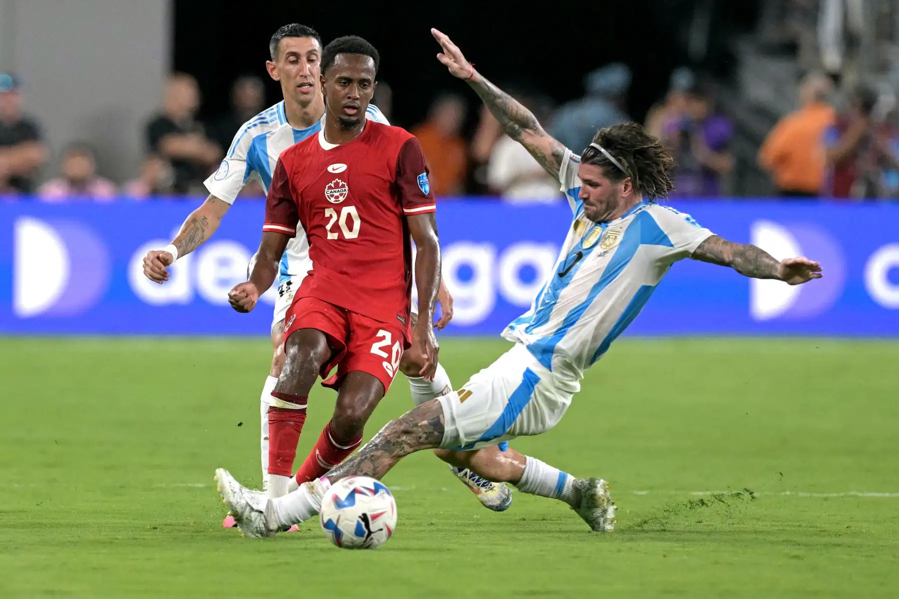 El mediocampista canadiense  Ali Ahmed lucha por el balón con el delantero argentino Angel Di Maria  y el mediocampista argentino Rodrigo De Paul durante el partido de fútbol semifinal del torneo Conmebol Copa América 2024 entre Argentina y Canadá. Foto: ANDINA//AFP