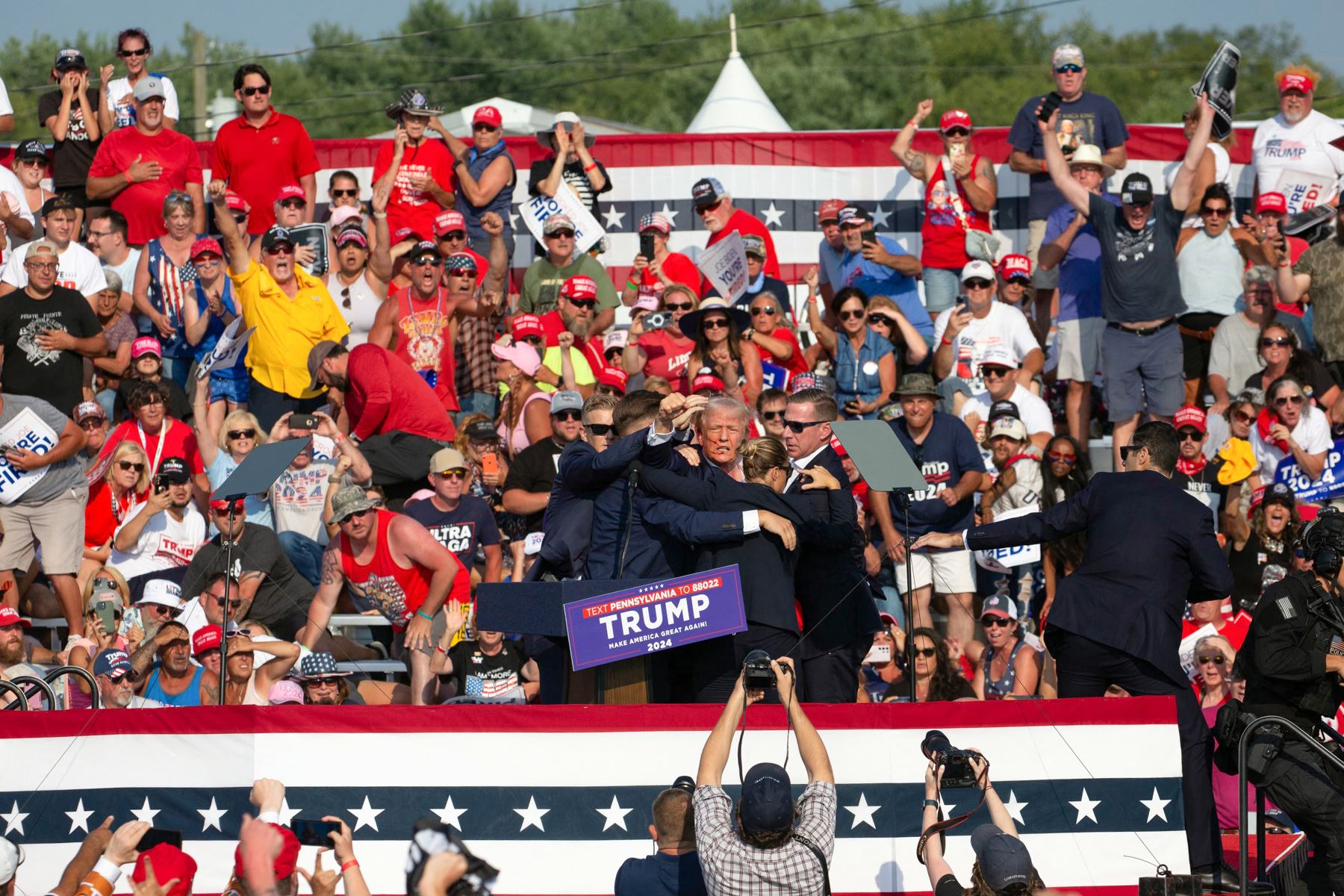 Se ve al candidato republicano Donald Trump con lo que parece ser sangre en el rostro rodeado de agentes del servicio secreto cuando lo sacan del escenario en un evento de campaña en Butler Farm Show Inc. en Butler, Pensilvania.
Foto: AFP