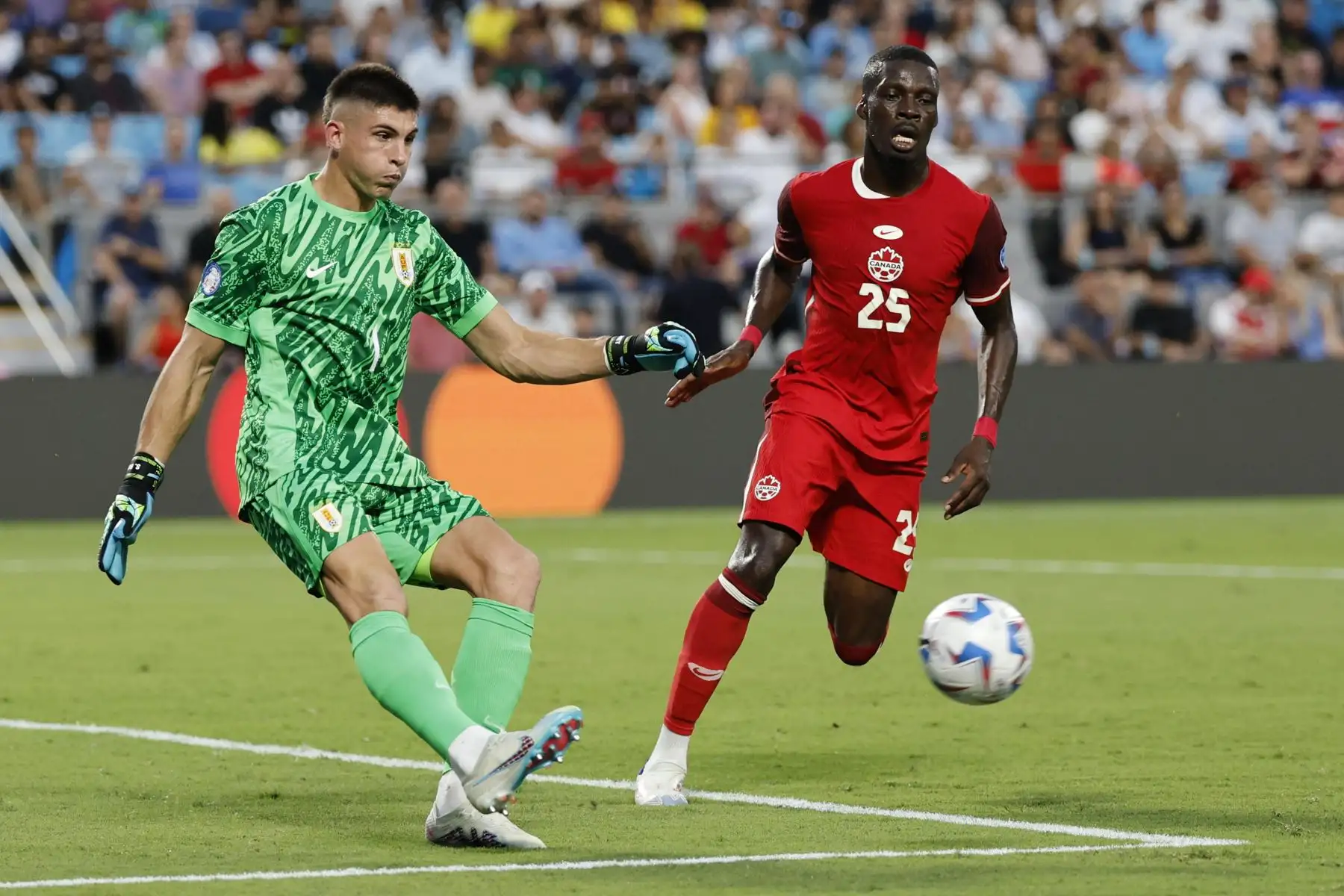 El portero uruguayo Sergio Rochet despeja el balón ante Tani Oluwaseyi de Canadá durante el partido por el tercer puesto de la CONMEBOL Copa América 2024 en Charlotte, Carolina del Norte.
Foto.: AFP